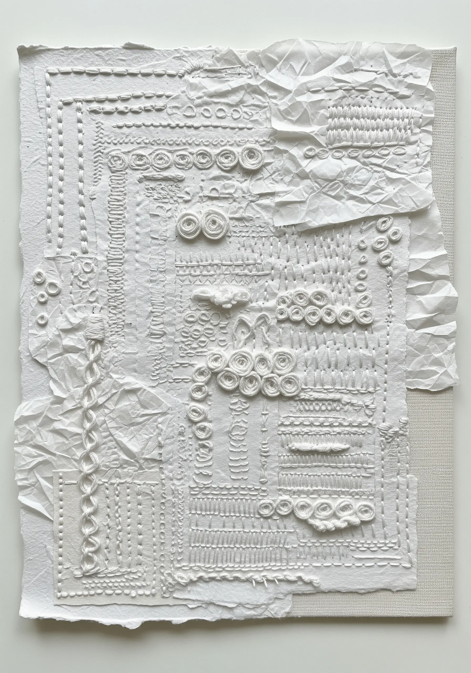 A white-on-white textural collage using crumpled paper and various embroidery stitches.