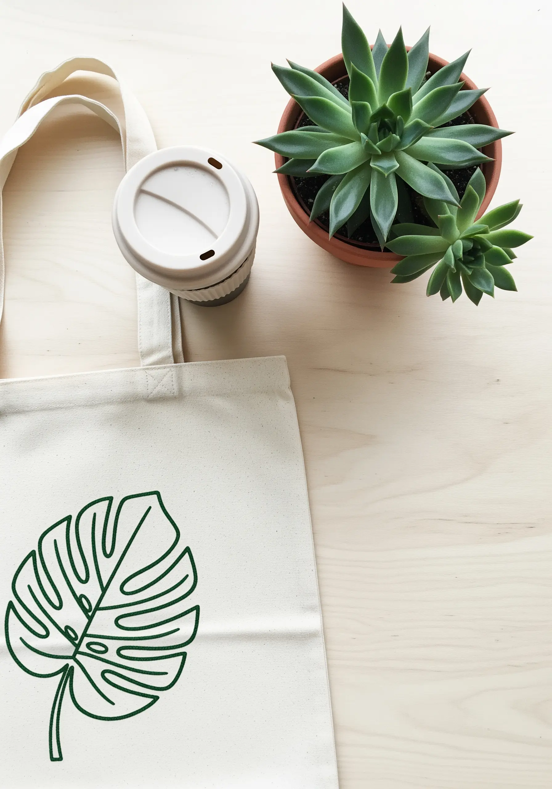 A large Monstera leaf outlined in green thread on a natural canvas tote bag.