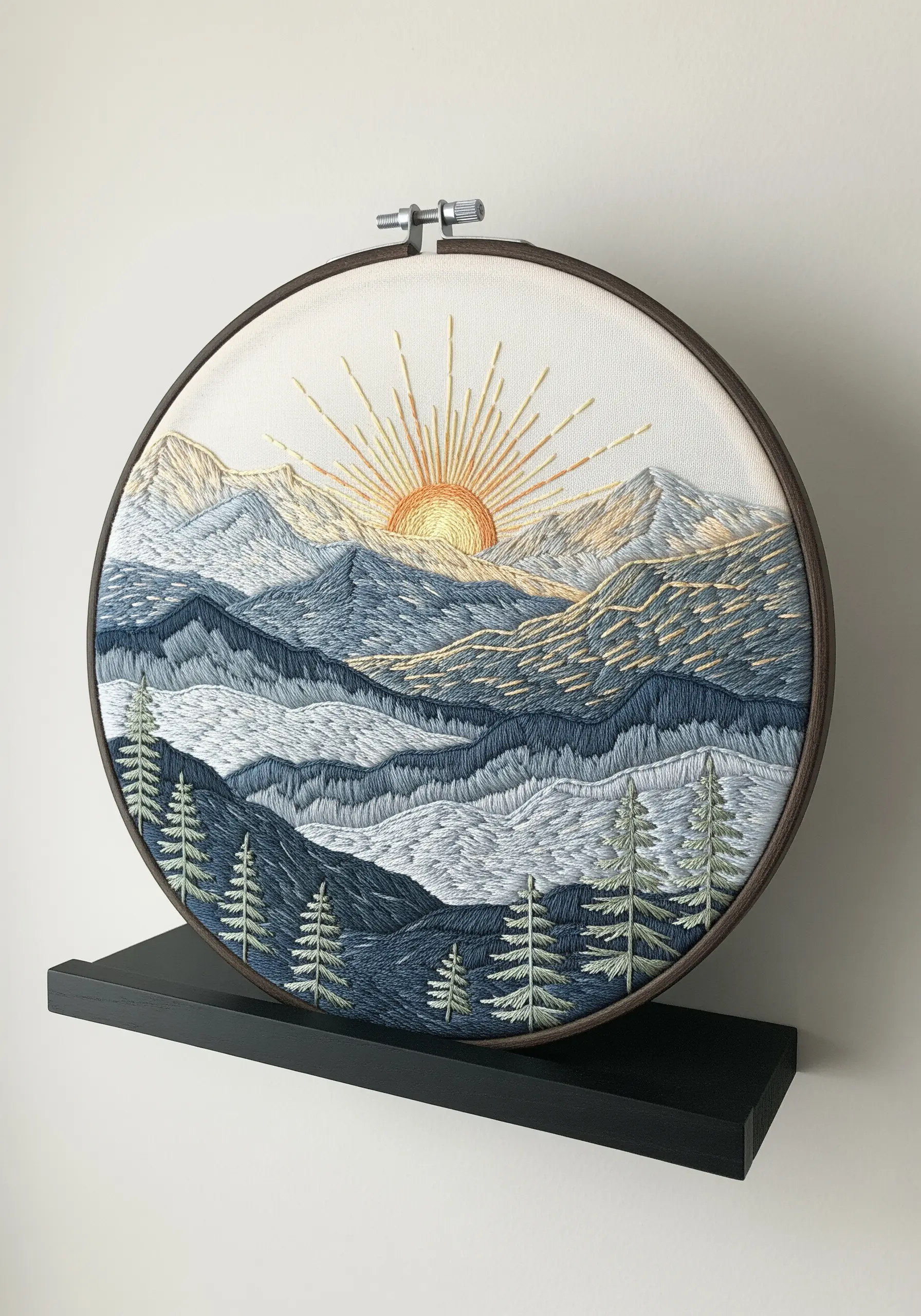 A mountain landscape embroidery with a sunrise, stitched in shades of blue and gold.