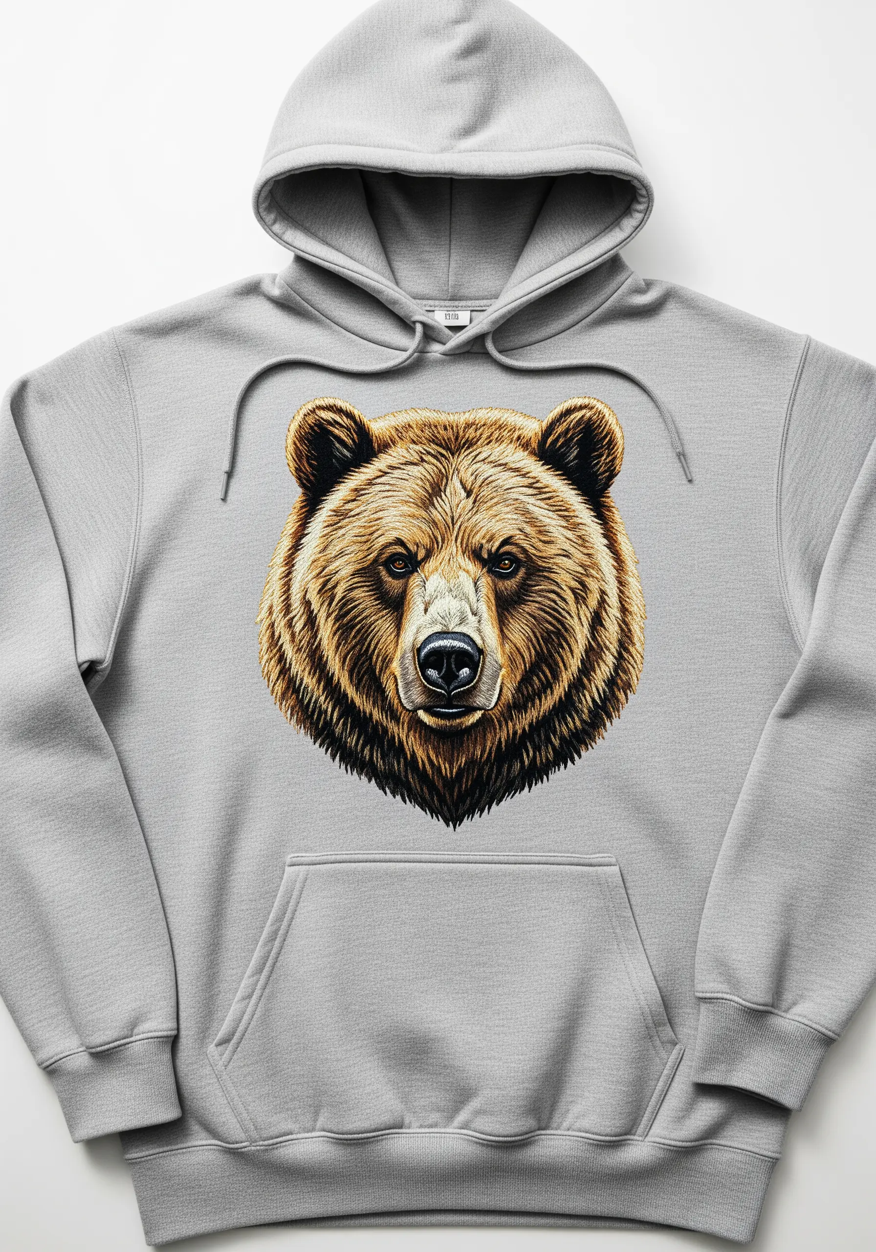 A highly realistic, thread-painted portrait of a grizzly bear on a grey hoodie.