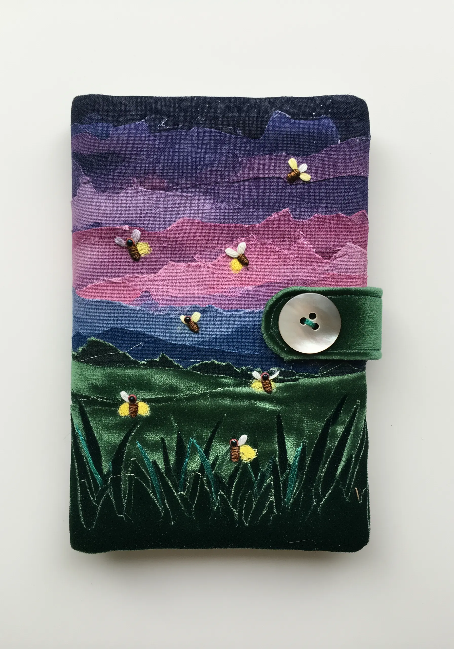 A journal cover with a torn-fabric collage sunset sky and embroidered fireflies.