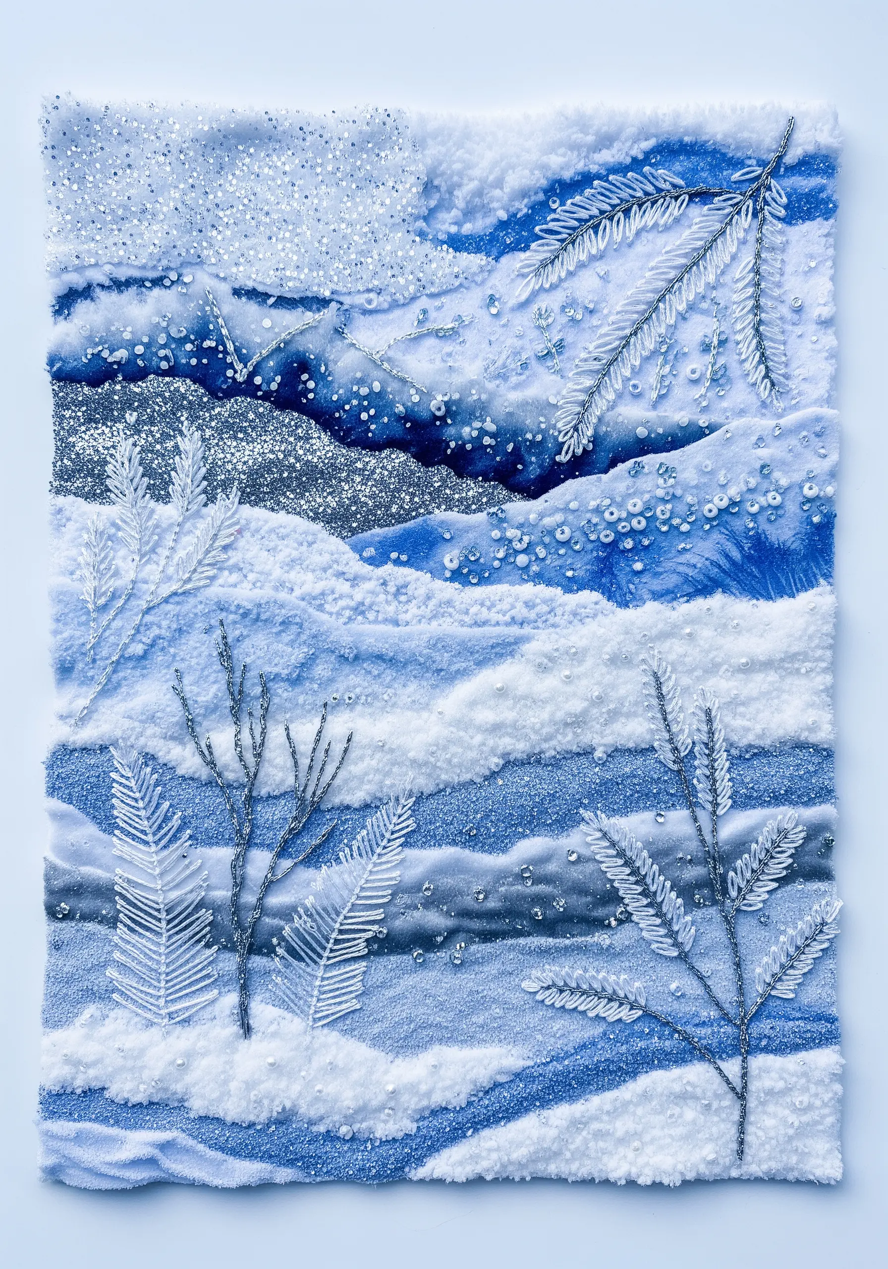 A textural winter landscape collage with white and blue fabrics, glitter, beads, and silver embroidery.