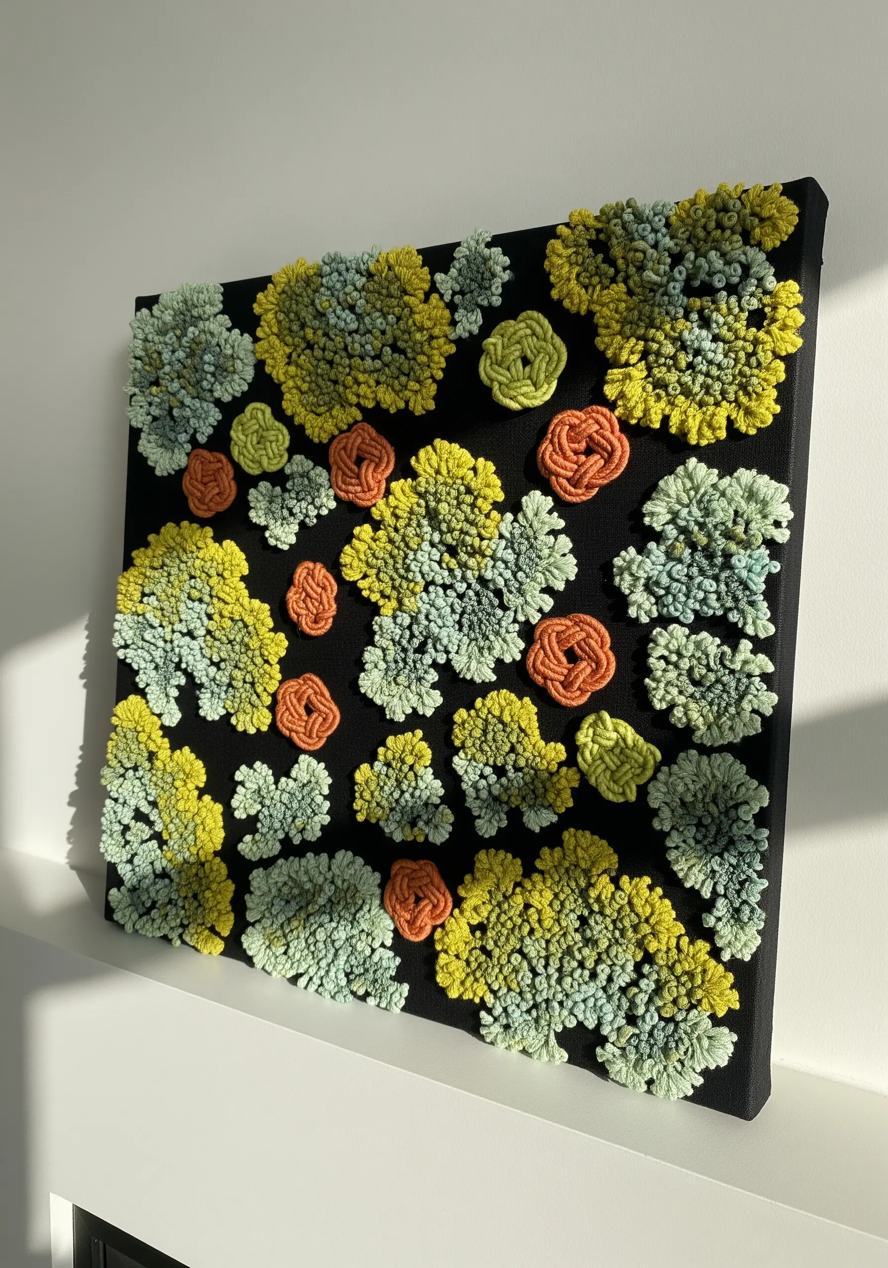Clusters of yellow, green, and orange French knots creating a lichen effect on a black canvas.