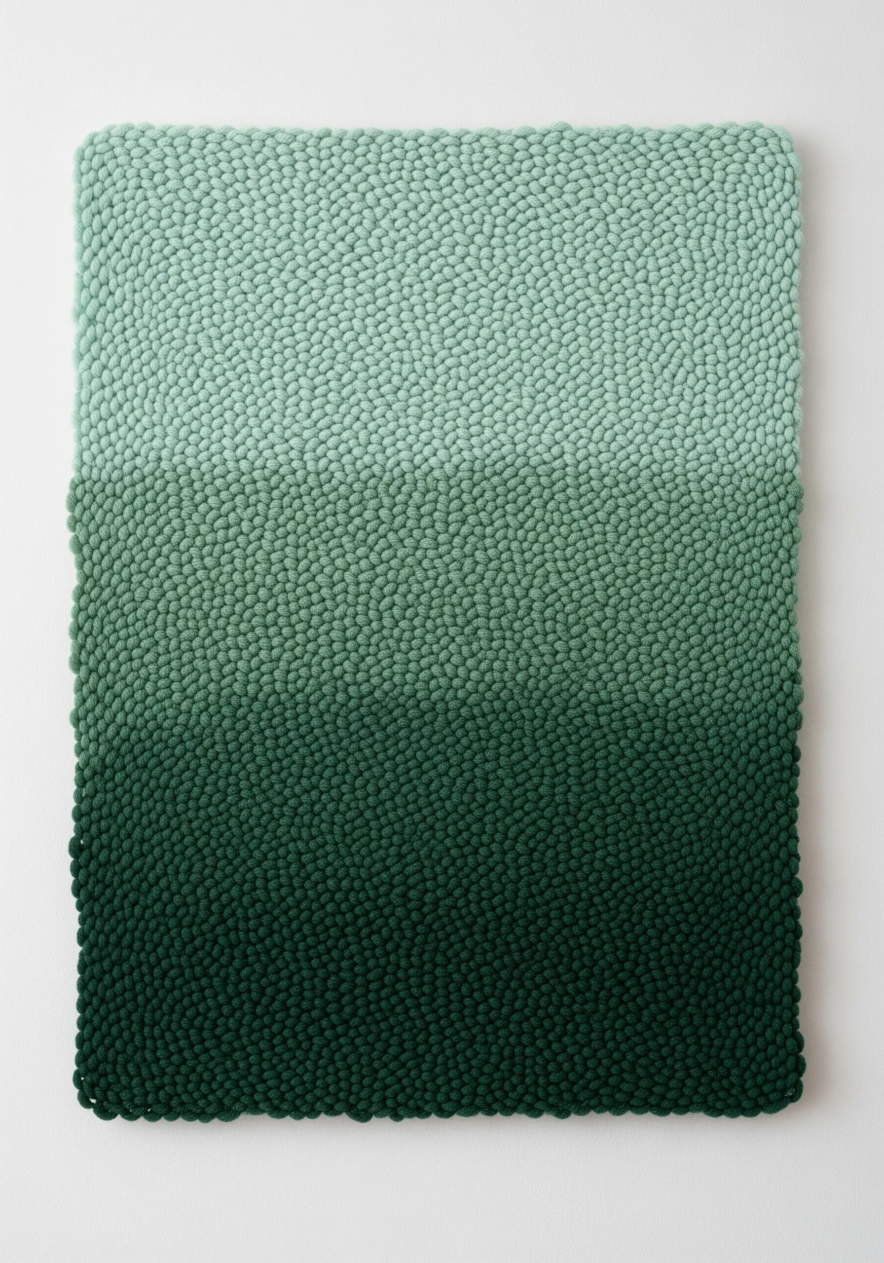 A rectangular textile art piece with a dense, bumpy texture transitioning from light to dark green.