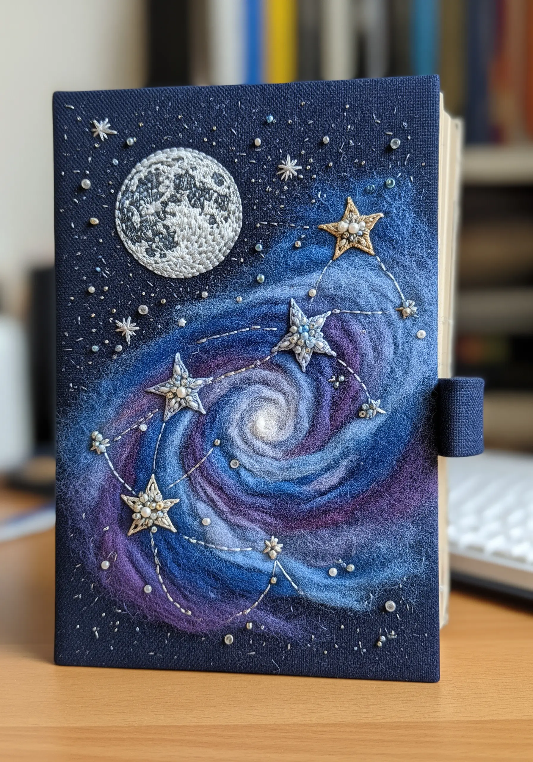 Journal cover with a needle-felted galaxy and an embroidered moon and constellations.
