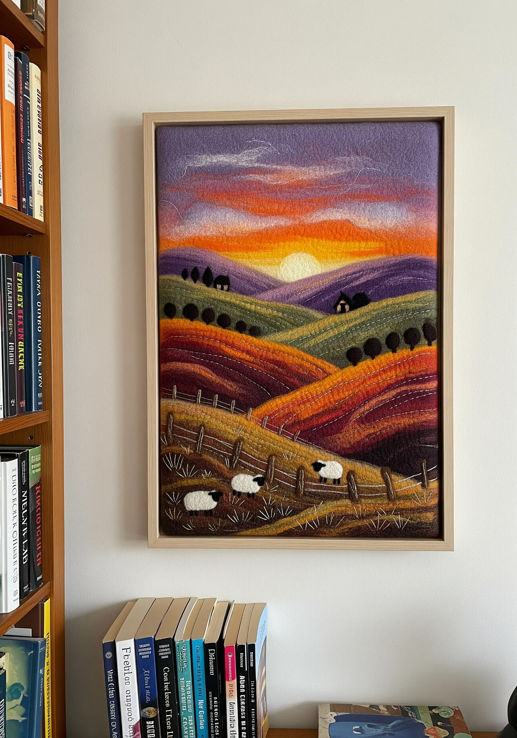 Needle-felted landscape of rolling hills at sunset with small embroidered sheep.