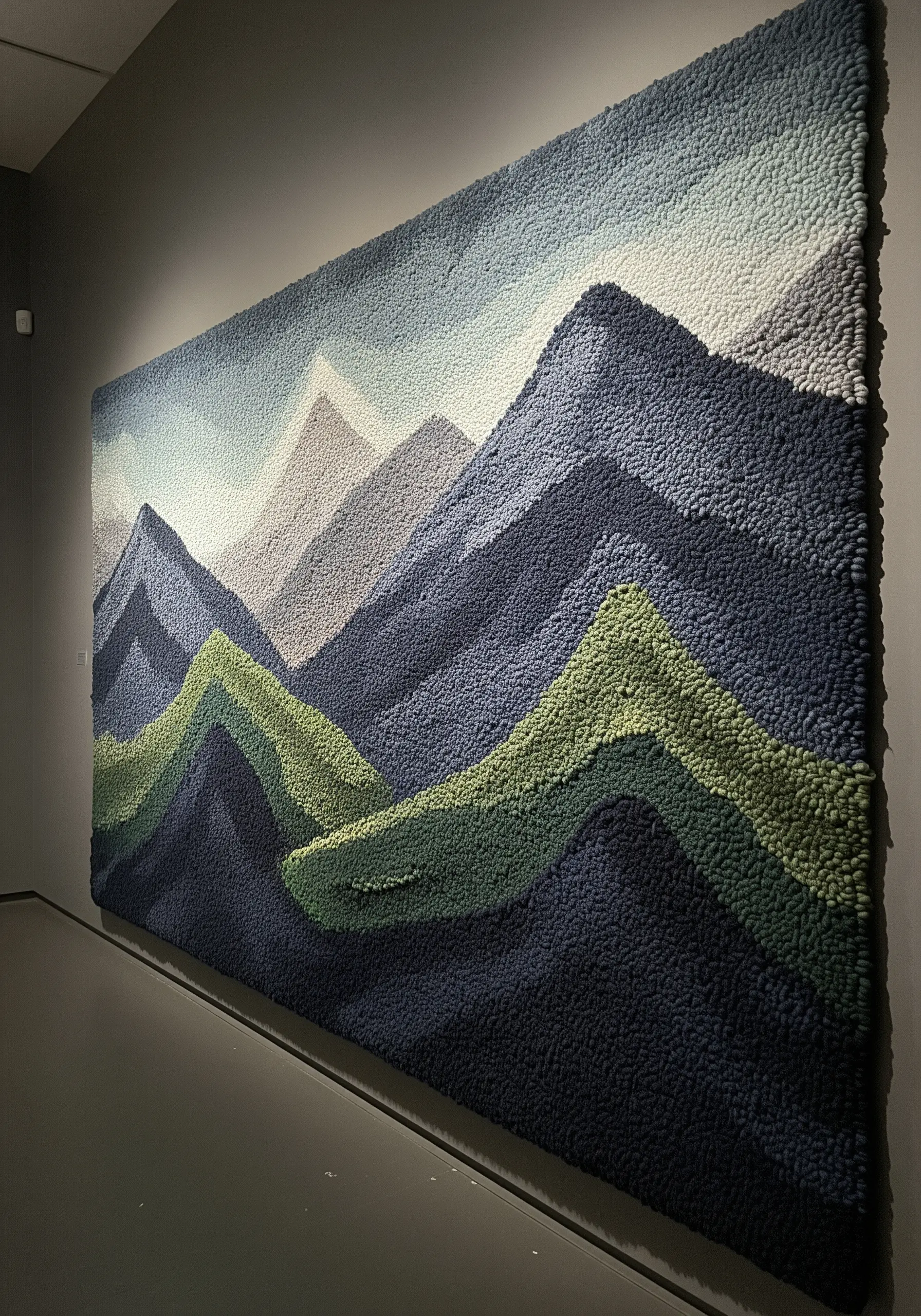 Large, tufted wall tapestry depicting a mountain range in shades of blue, green, and grey.