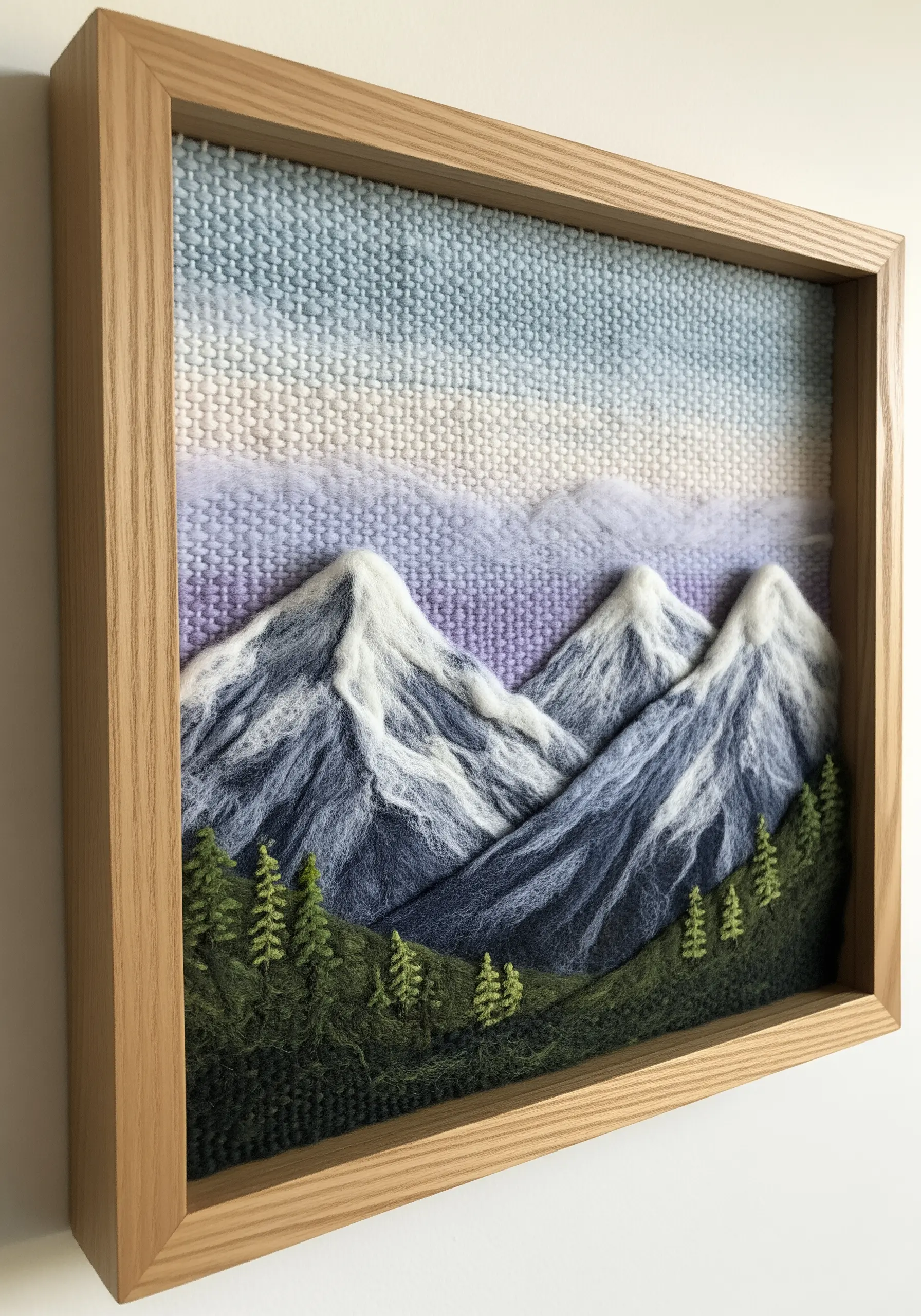 A needle-felted mountain landscape in a shadow box frame, showing realistic, textured peaks.