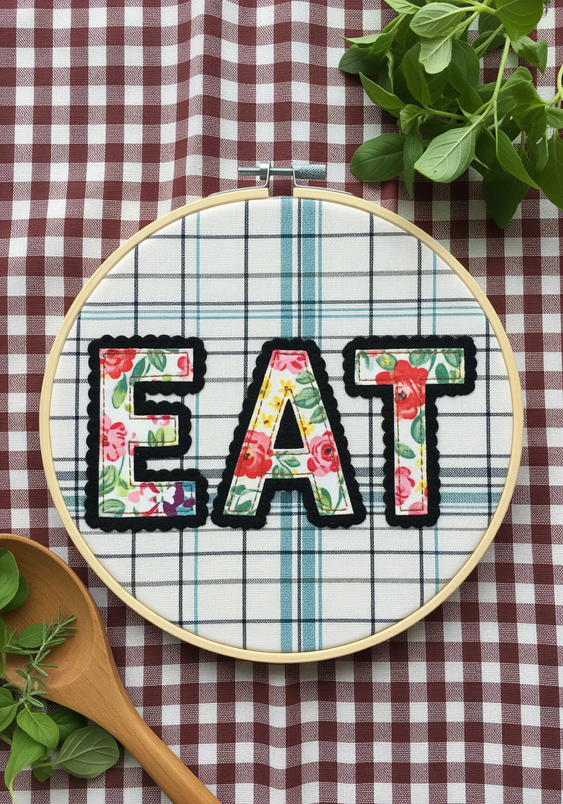 Floral fabric appliqué letters spelling EAT with black blanket stitch outline