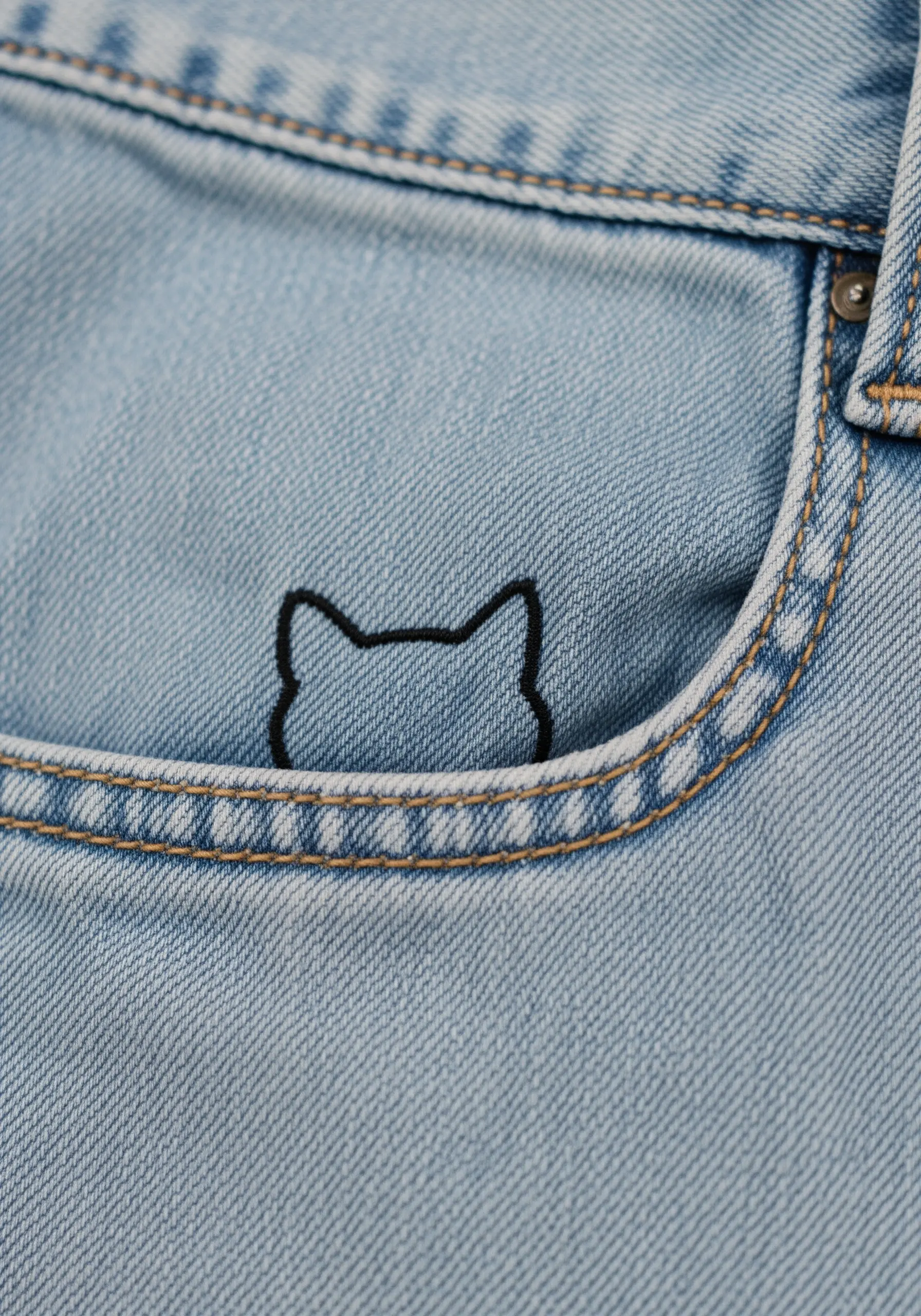 A black outline of a cat head peeking out from the coin pocket of blue jeans.