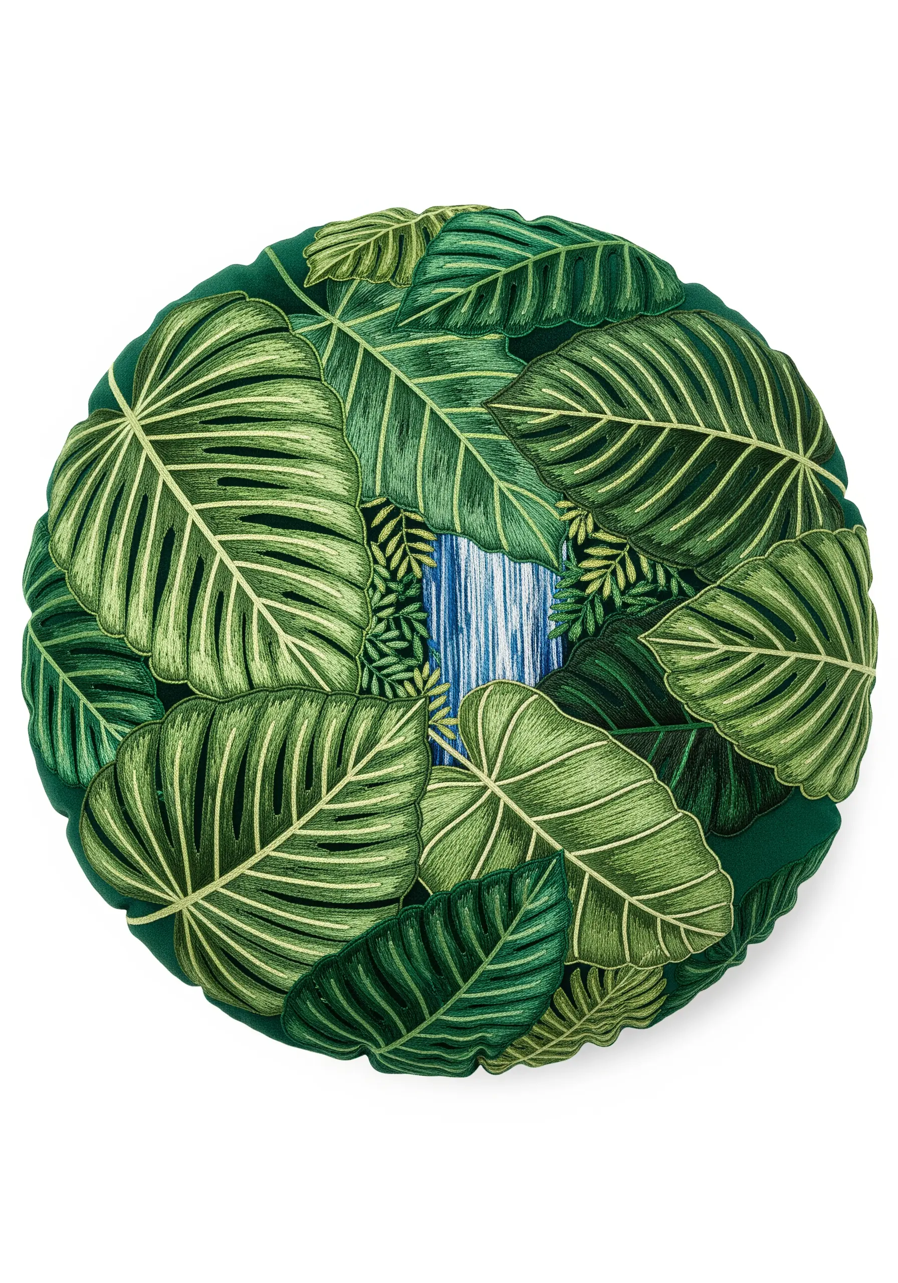 A round green pillow covered in embroidered tropical leaves with a waterfall visible between them.