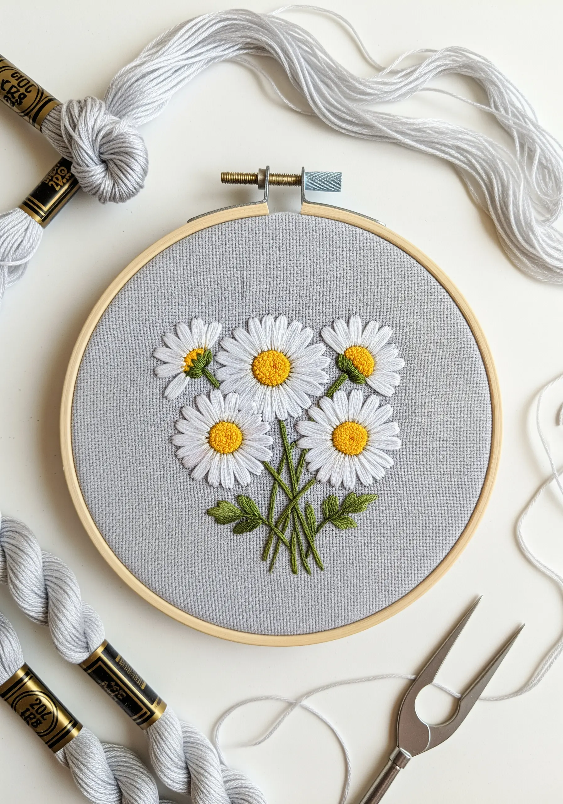 A bouquet of five white daisies with yellow centers stitched on gray cotton fabric.