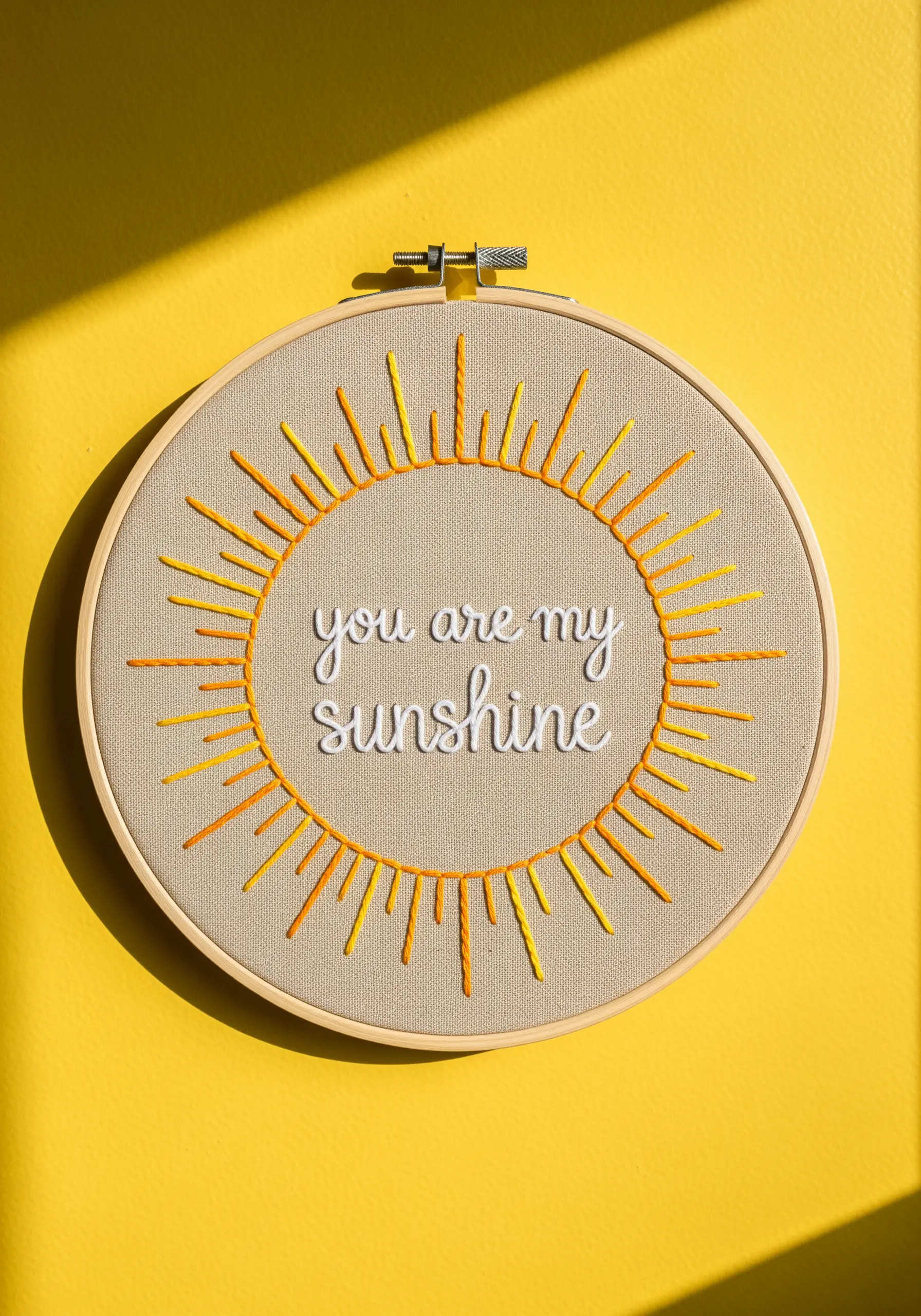 An embroidery hoop with the quote 'you are my sunshine' and stylized sun rays.