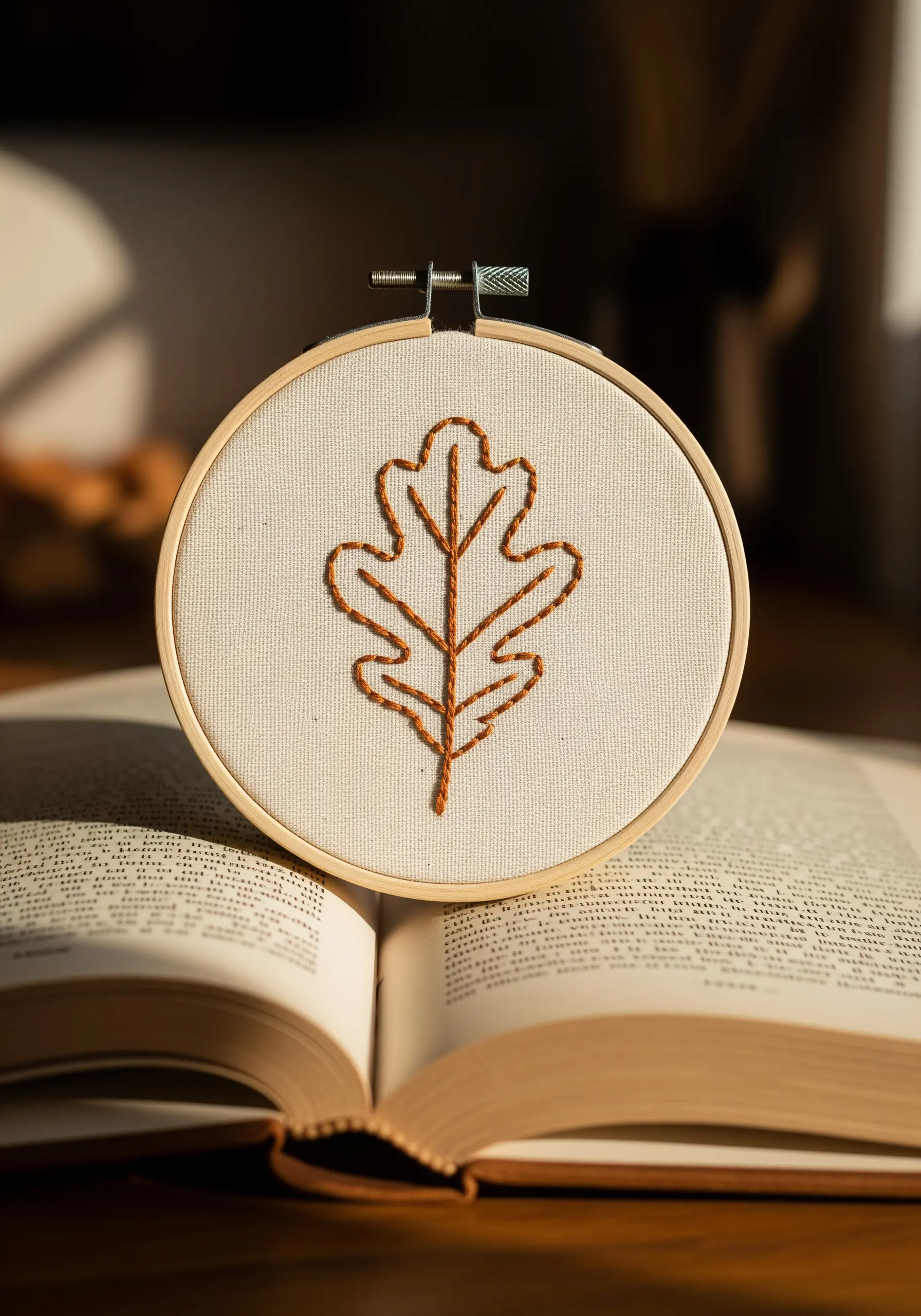 A simple oak leaf outline embroidered in rust-colored thread on off-white canvas.