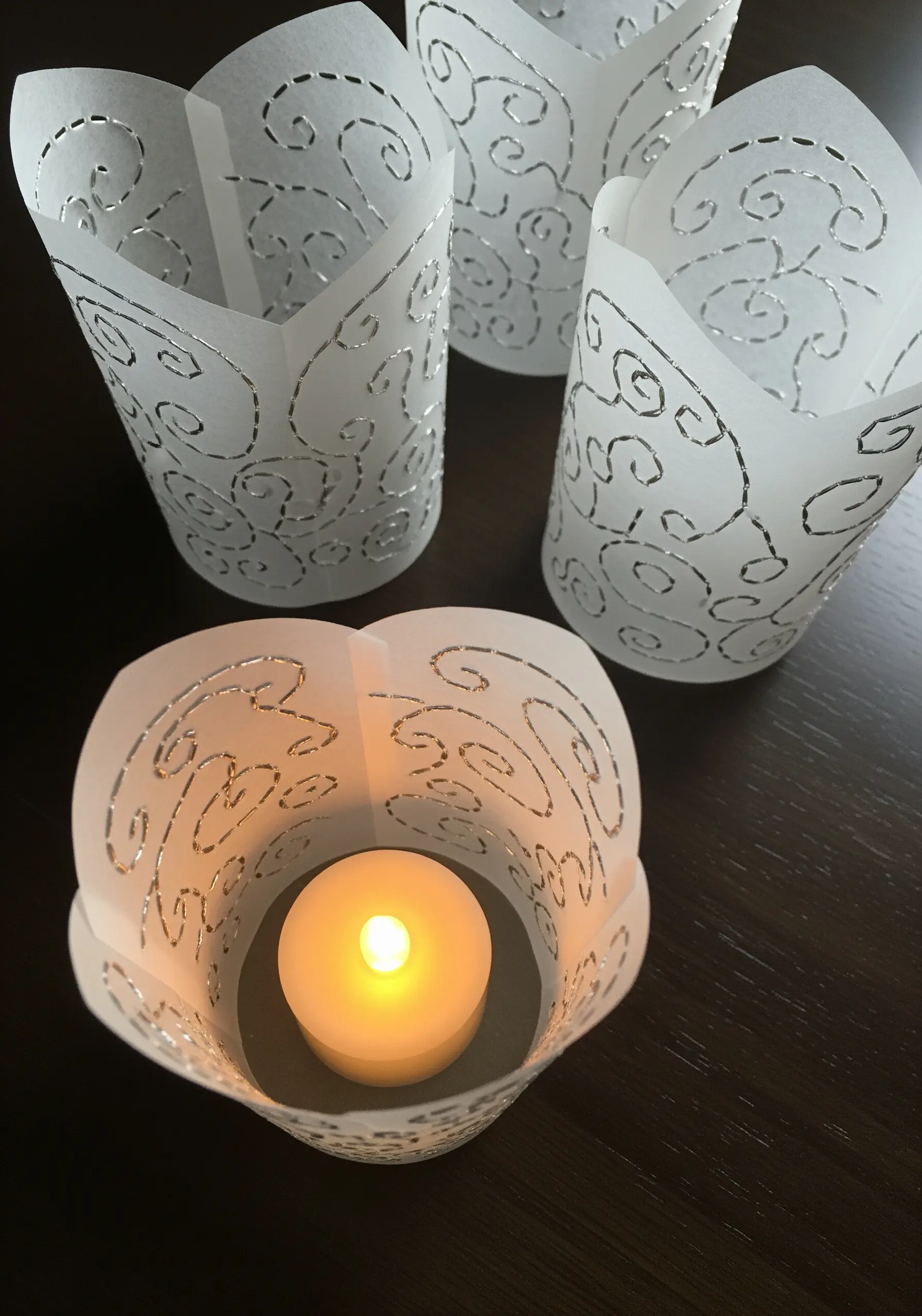 Translucent paper lanterns illuminated from within, showing stitched swirl patterns.