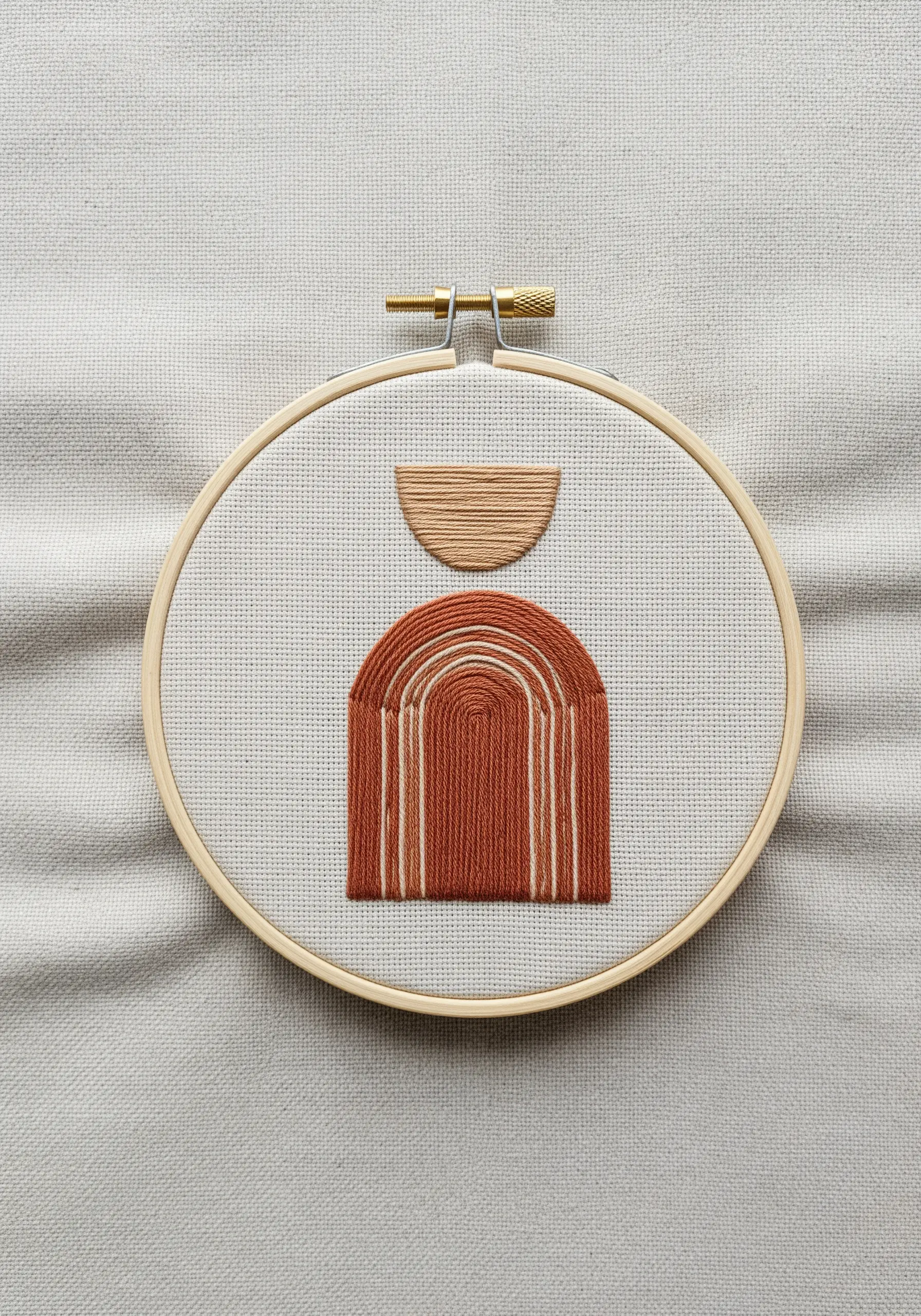 Abstract geometric arches stitched in terracotta and cream, using negative space and varied stitch direction.