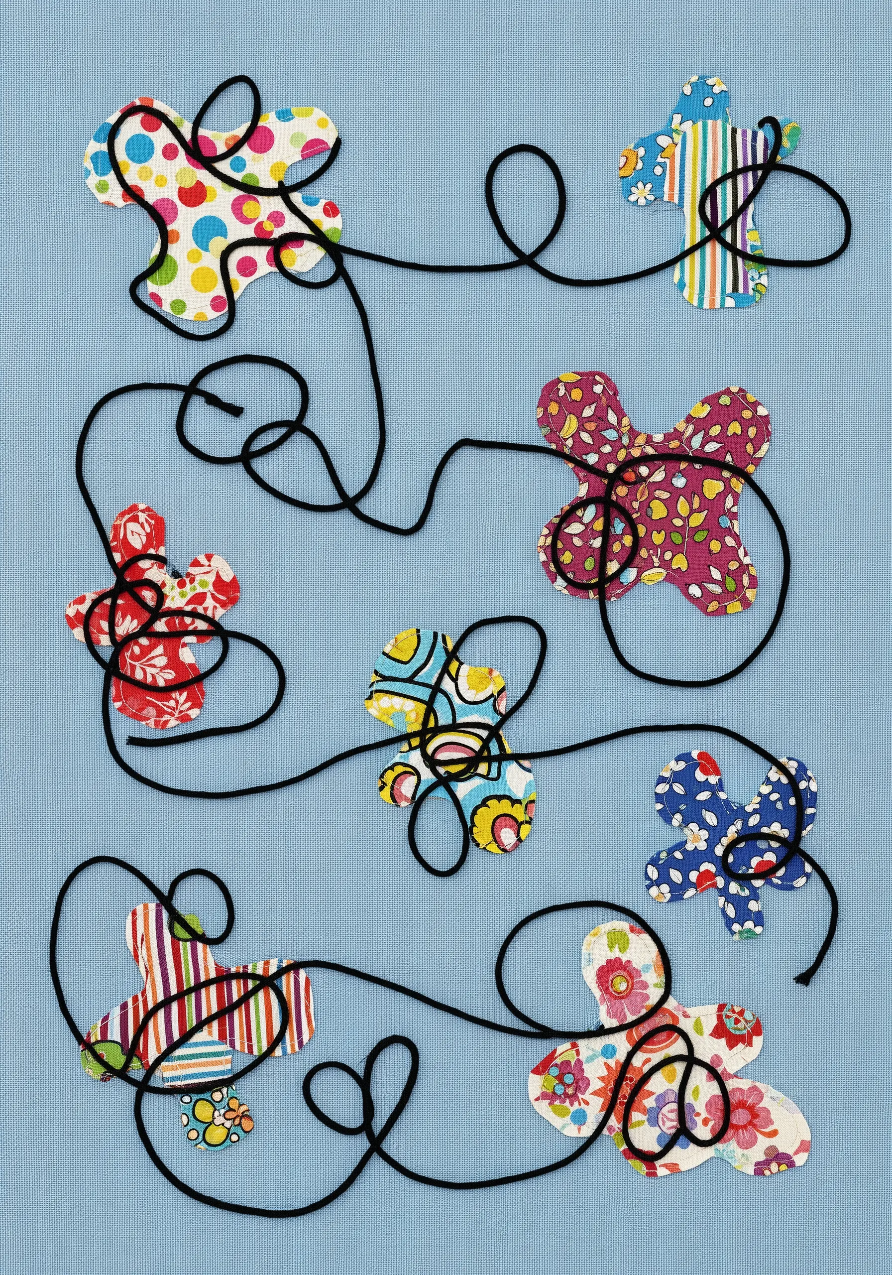 Colorful patterned fabric shapes on blue background, connected by a meandering black cord.