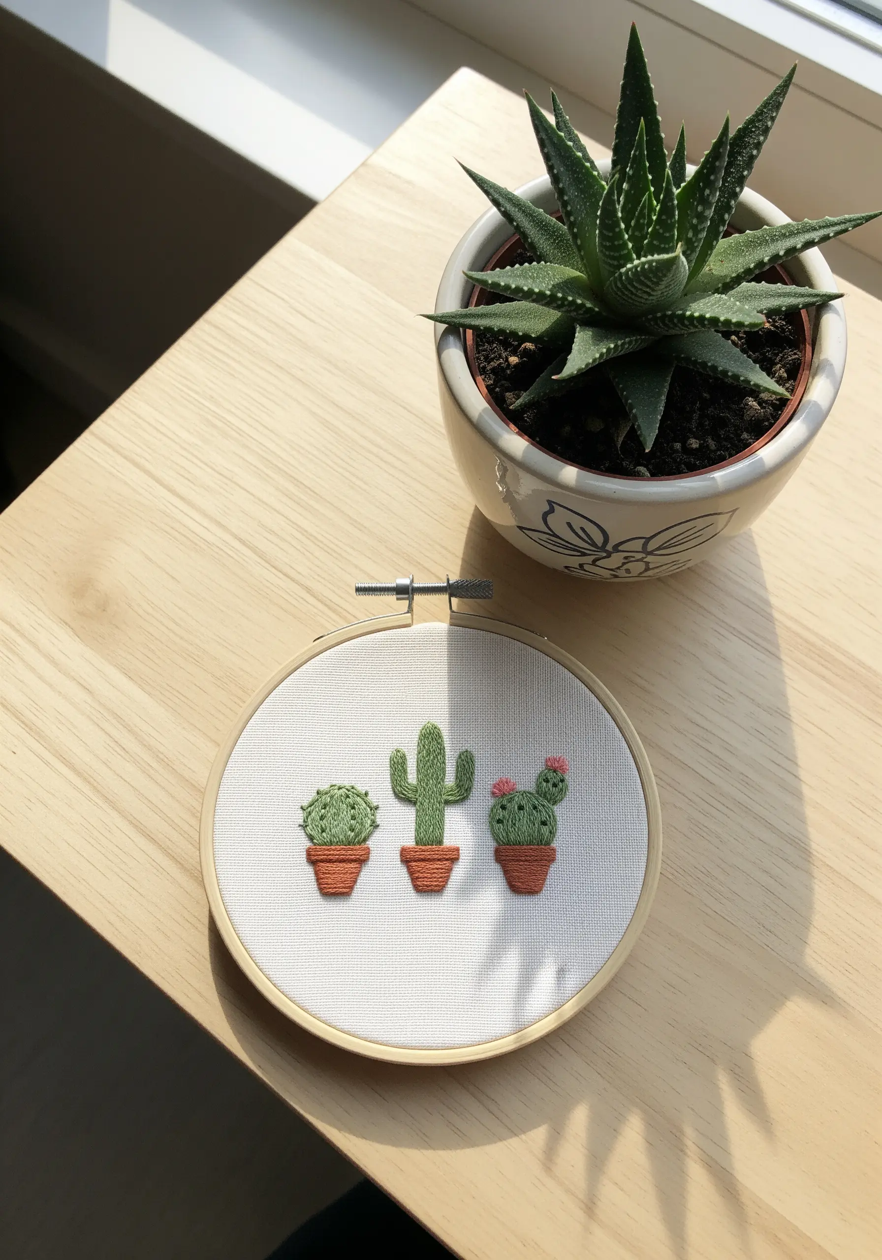 Three small embroidered cacti in terracotta pots, each with a different stitch texture.