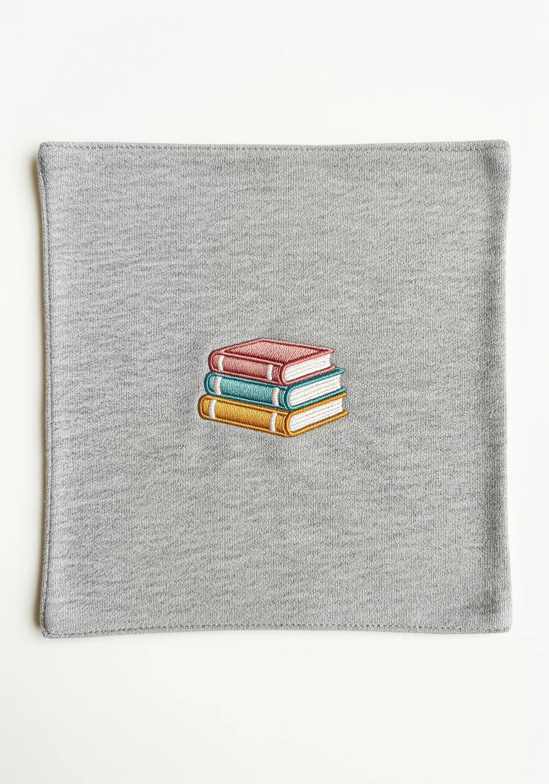 A tiny stack of three colorful books embroidered with clean satin stitch and outlines.