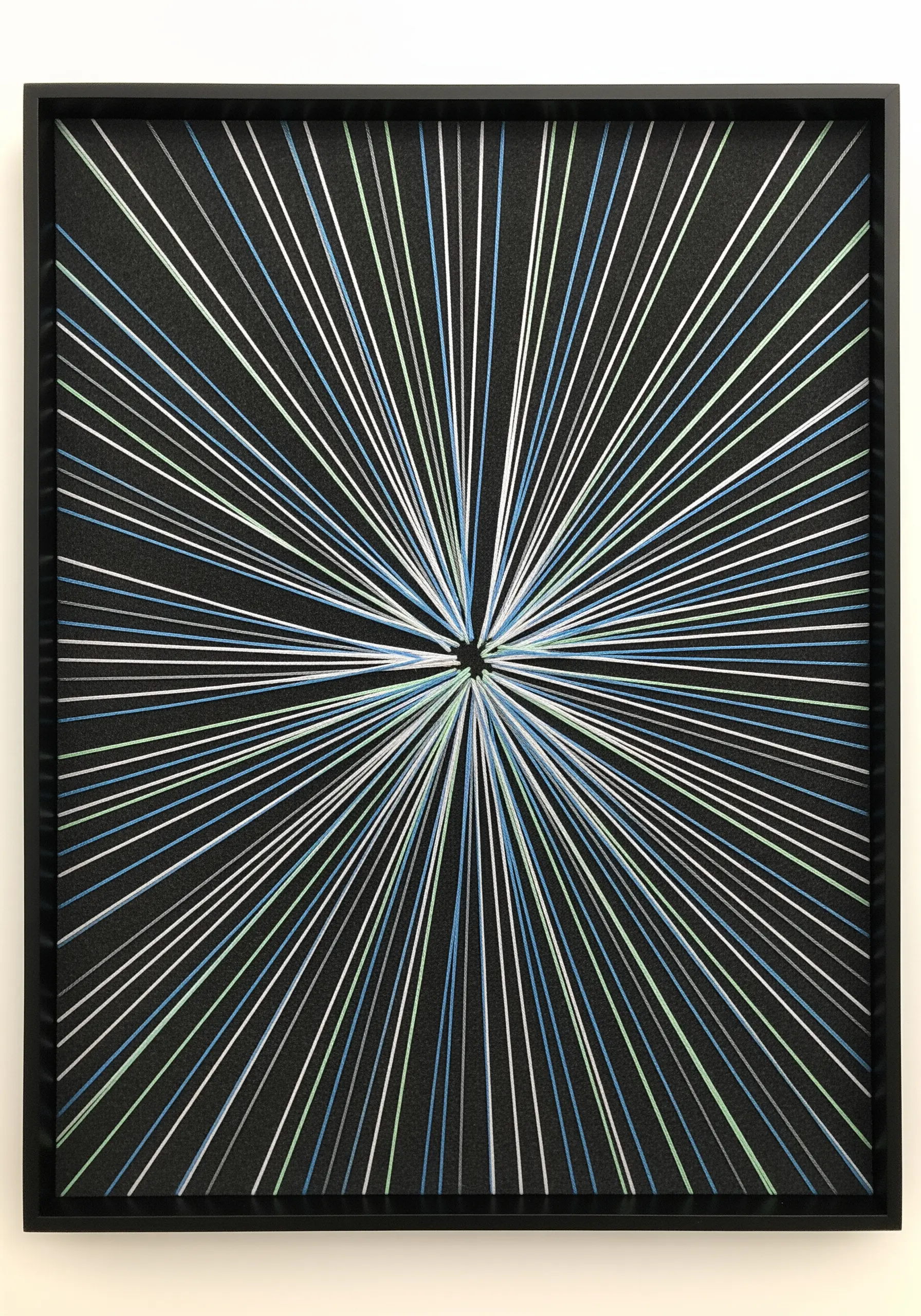 A radial starburst embroidery with white, green, and blue threads radiating from the center.