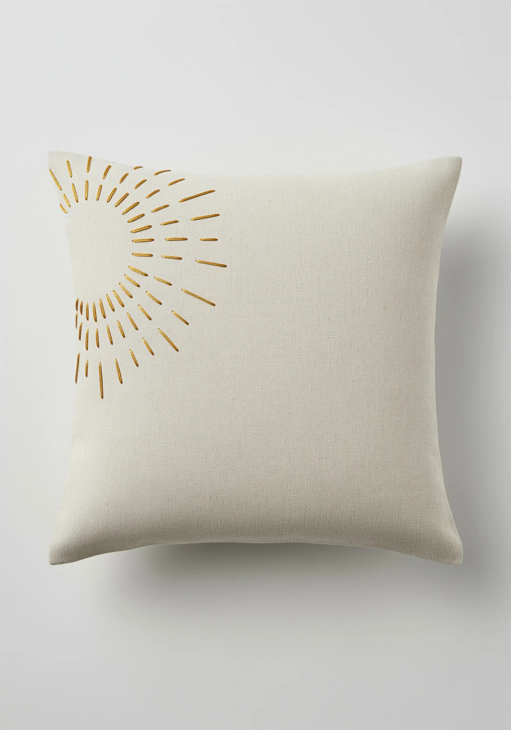 Minimalist sunburst embroidered with gold metallic thread on a natural linen pillow.
