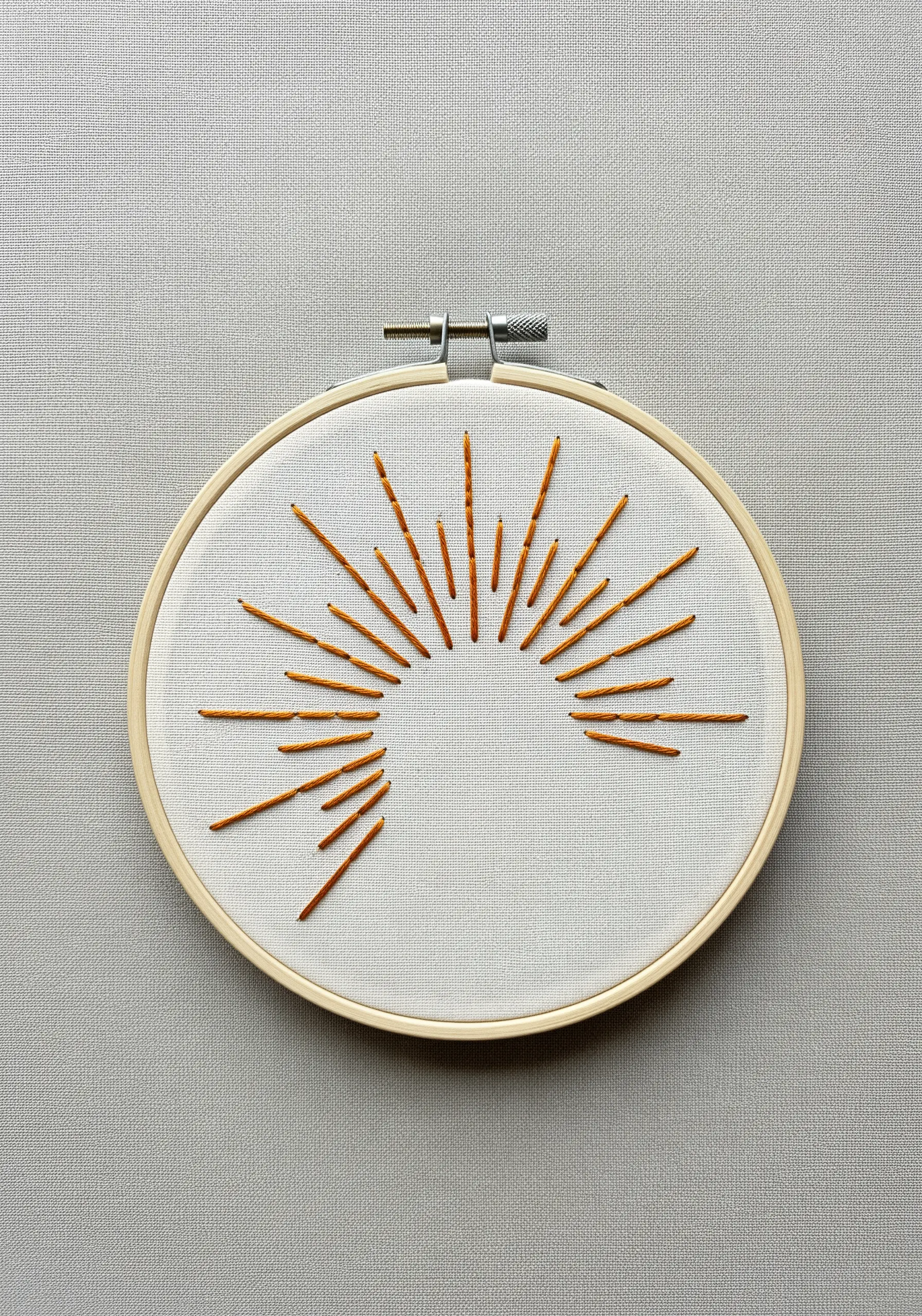 A minimalist sunburst design using straight stitches of varying lengths in orange thread.