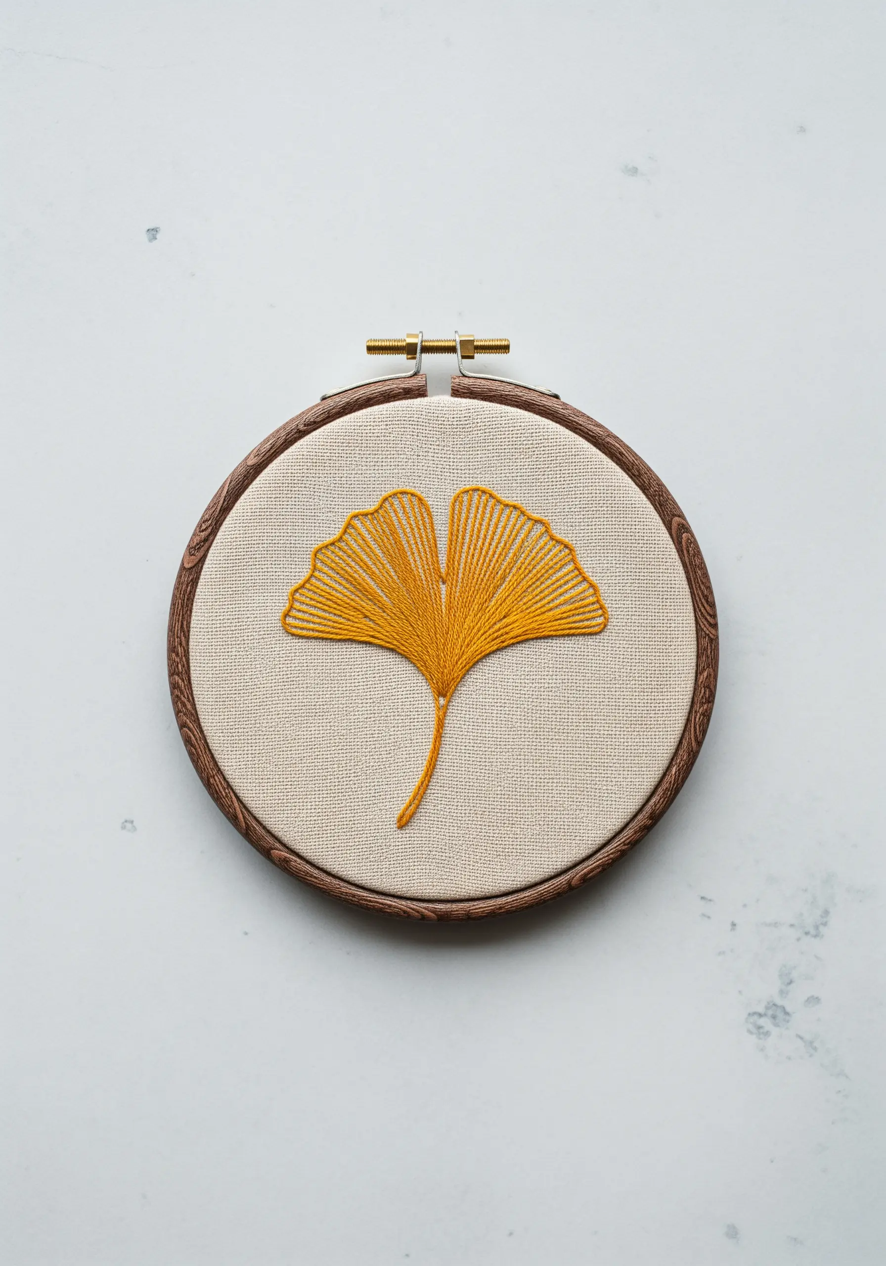 A single ginkgo leaf embroidered in golden yellow thread with radiating stitches.