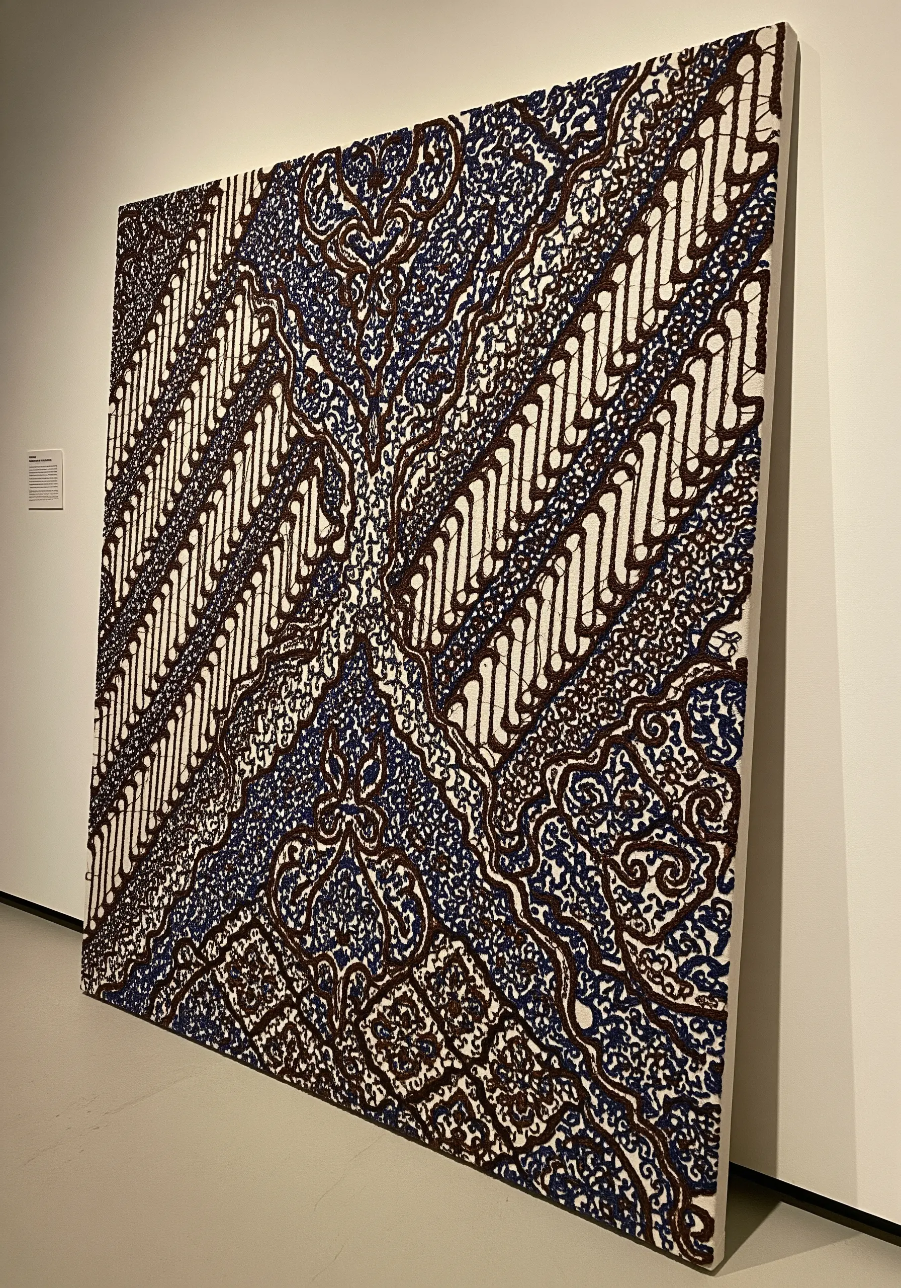 A large Indonesian Batik fabric panel with intricate patterns in blue, brown, and cream.
