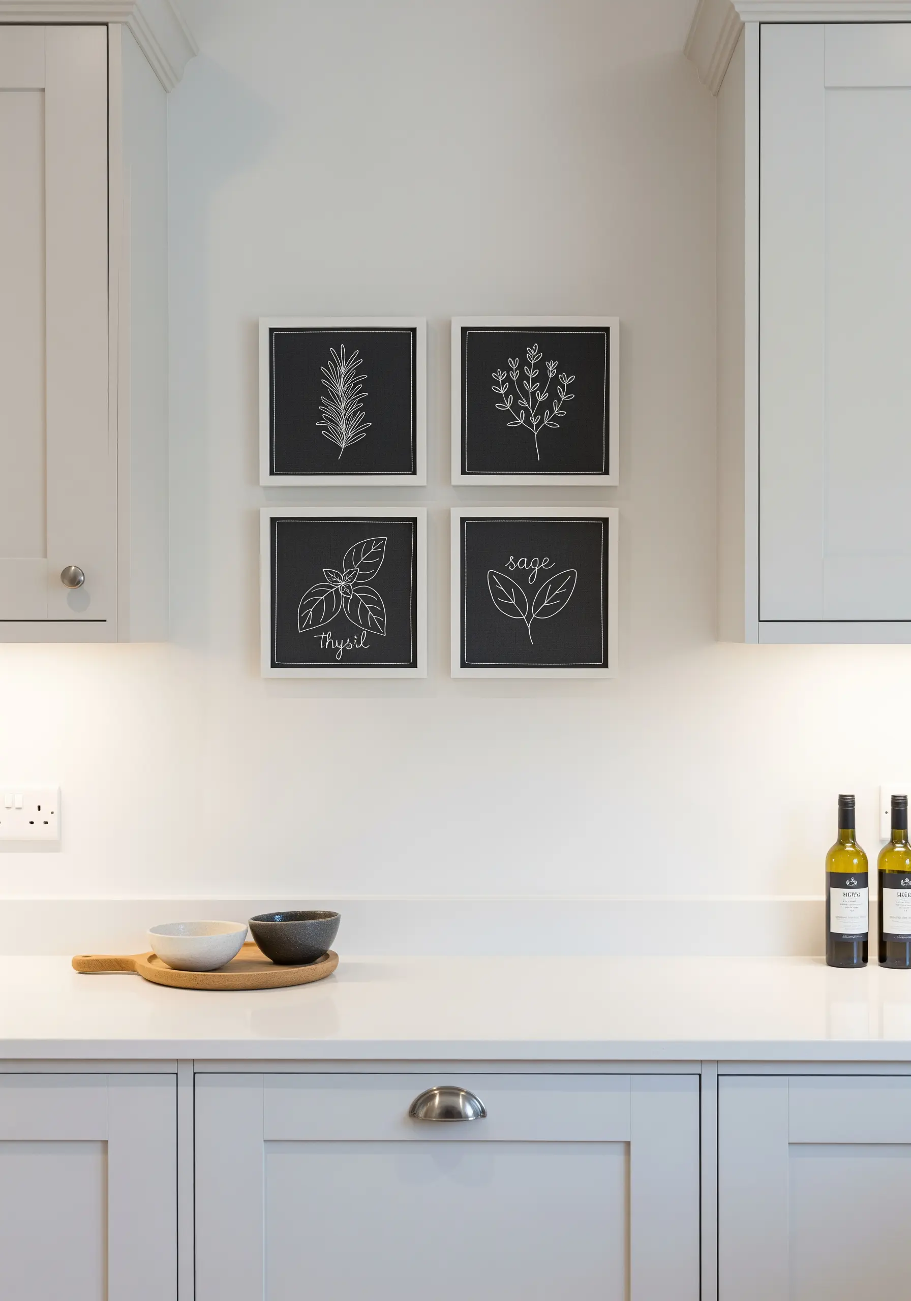 A set of four framed line-art herb embroideries in white thread on black fabric.