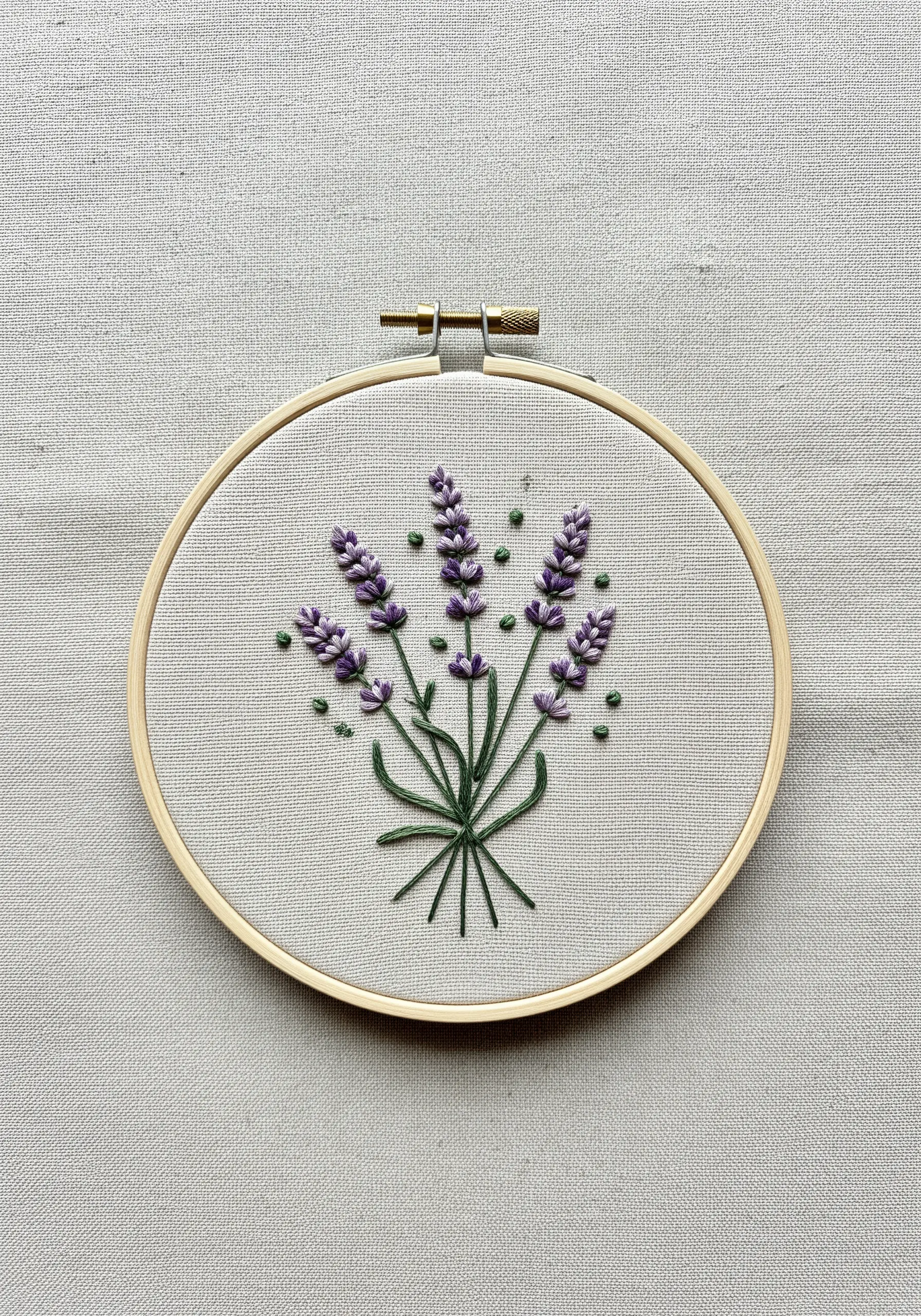 A hand-embroidered lavender bouquet with French knots in a wooden hoop.
