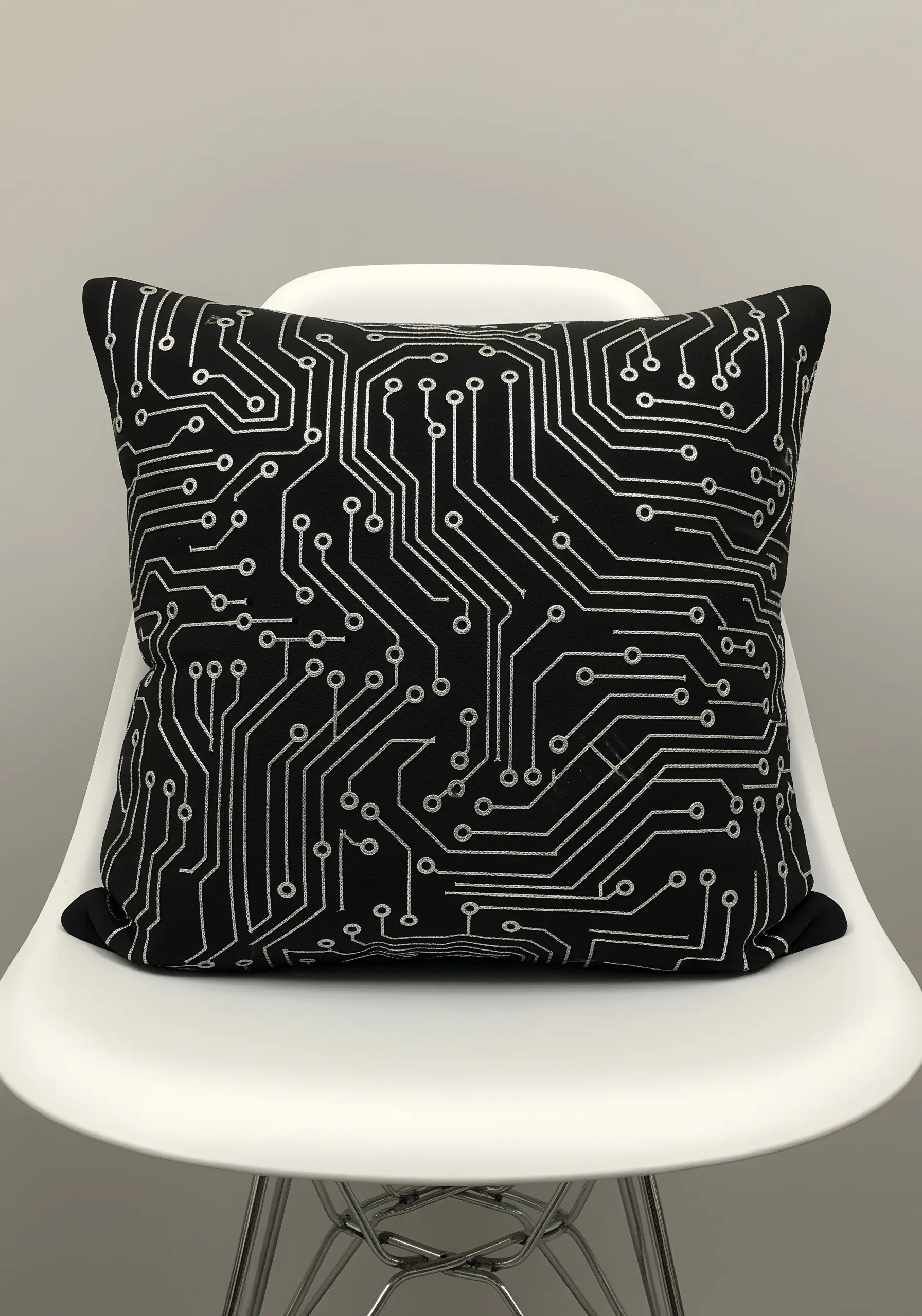 A black pillow with a circuit board pattern stitched in a reflective silver metallic thread.