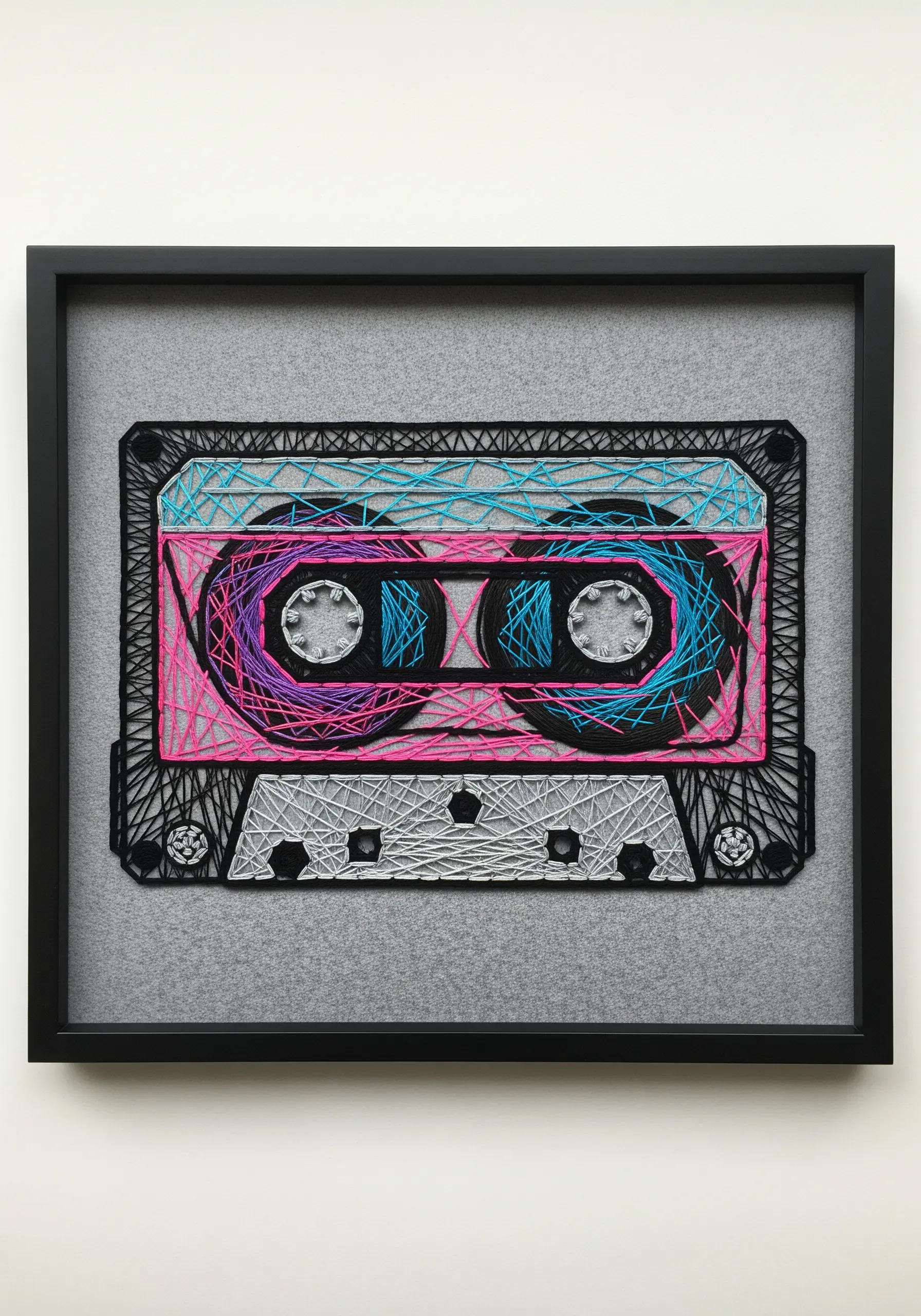 A retro cassette tape embroidered with different stitch textures for the body and spools.