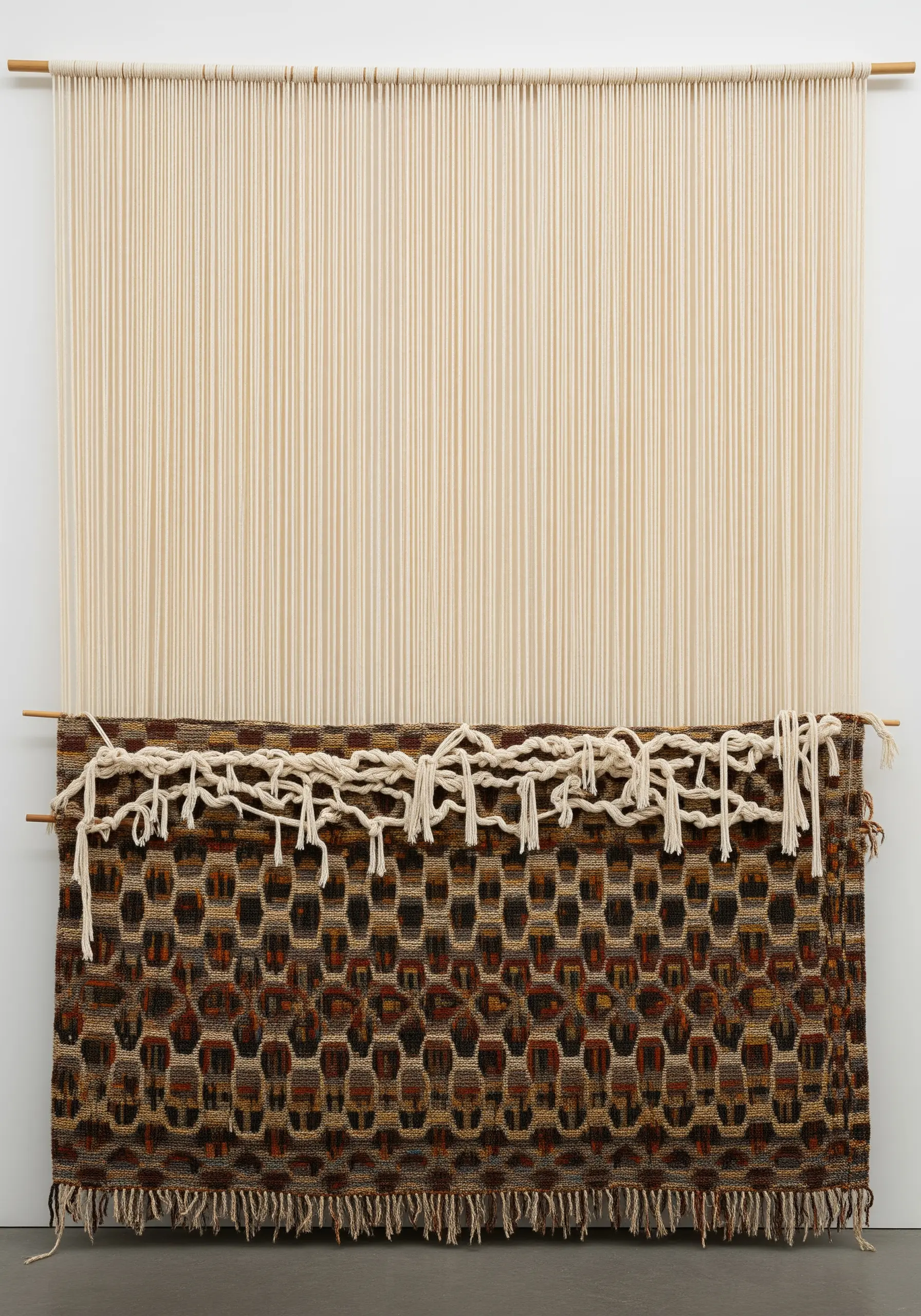 A weaving on a loom, intentionally left half-finished with exposed warp threads at the top.