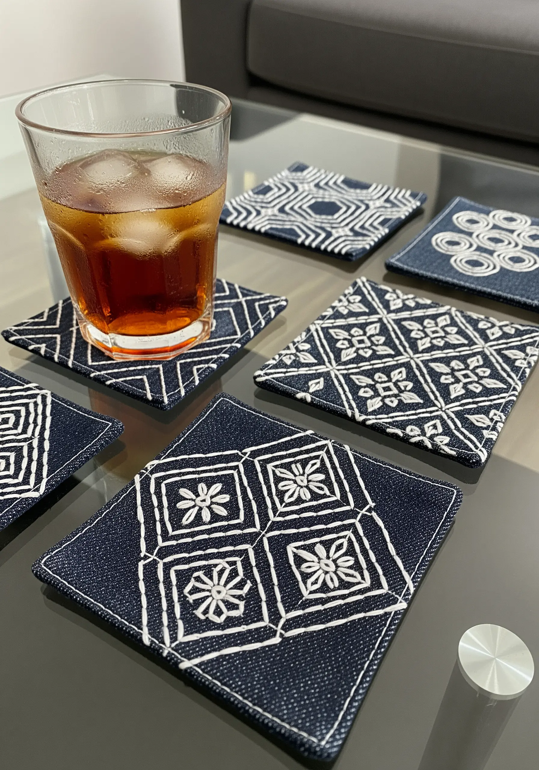 Set of navy blue denim coasters with white geometric sashiko embroidery patterns