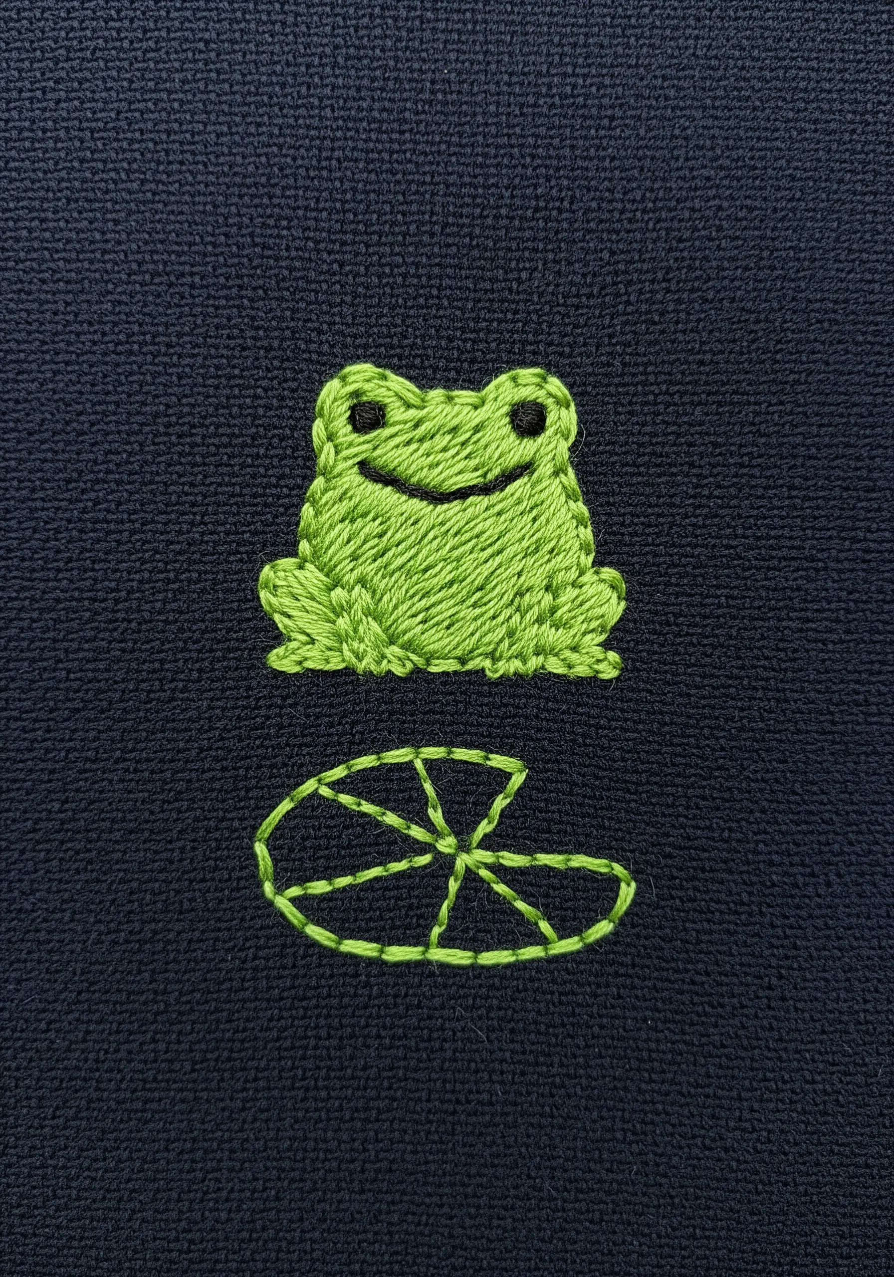 Bright green frog embroidery with satin stitch filling and a lily pad