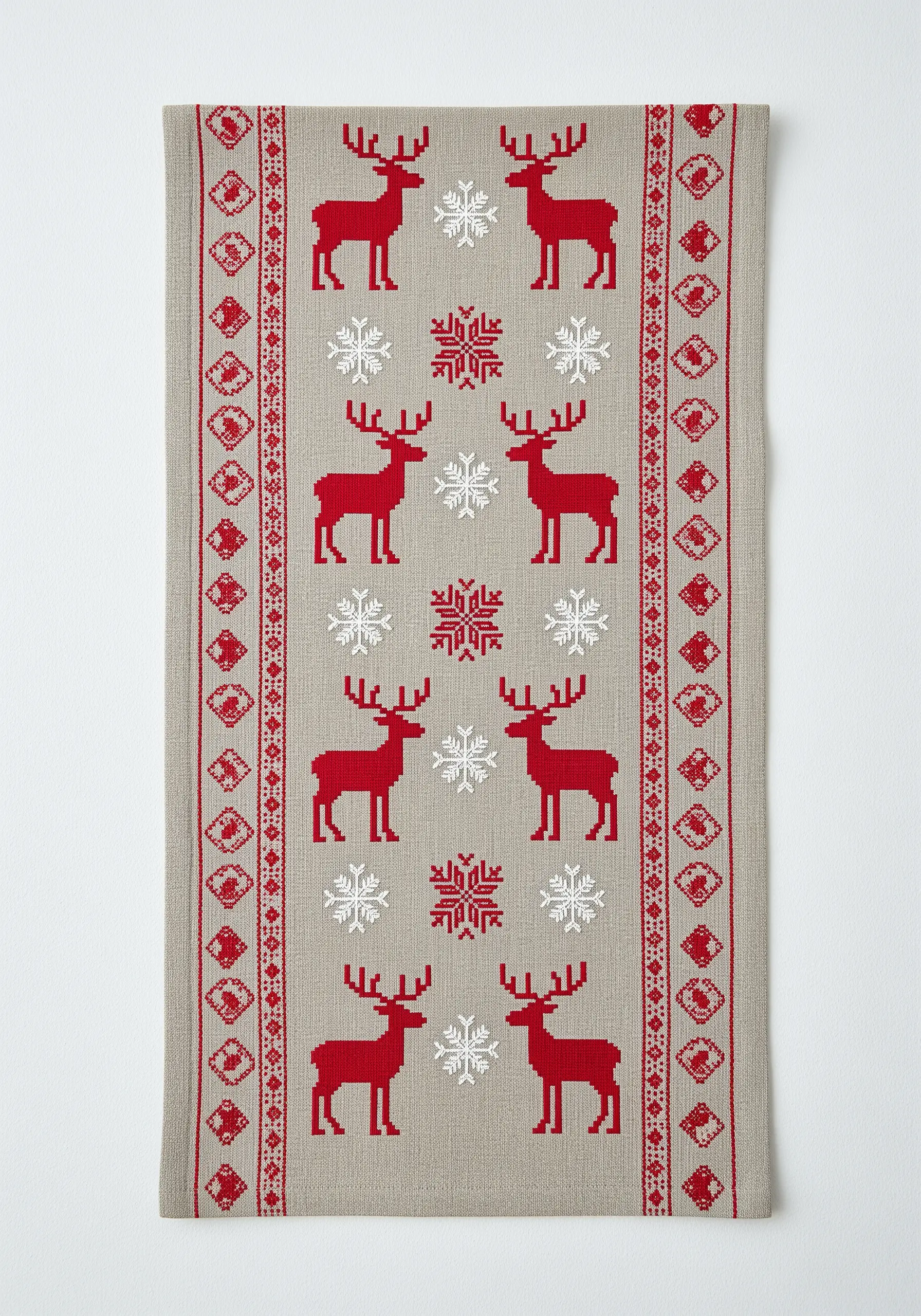 Scandinavian-style cross-stitch pattern of red reindeer and snowflakes on a linen runner.