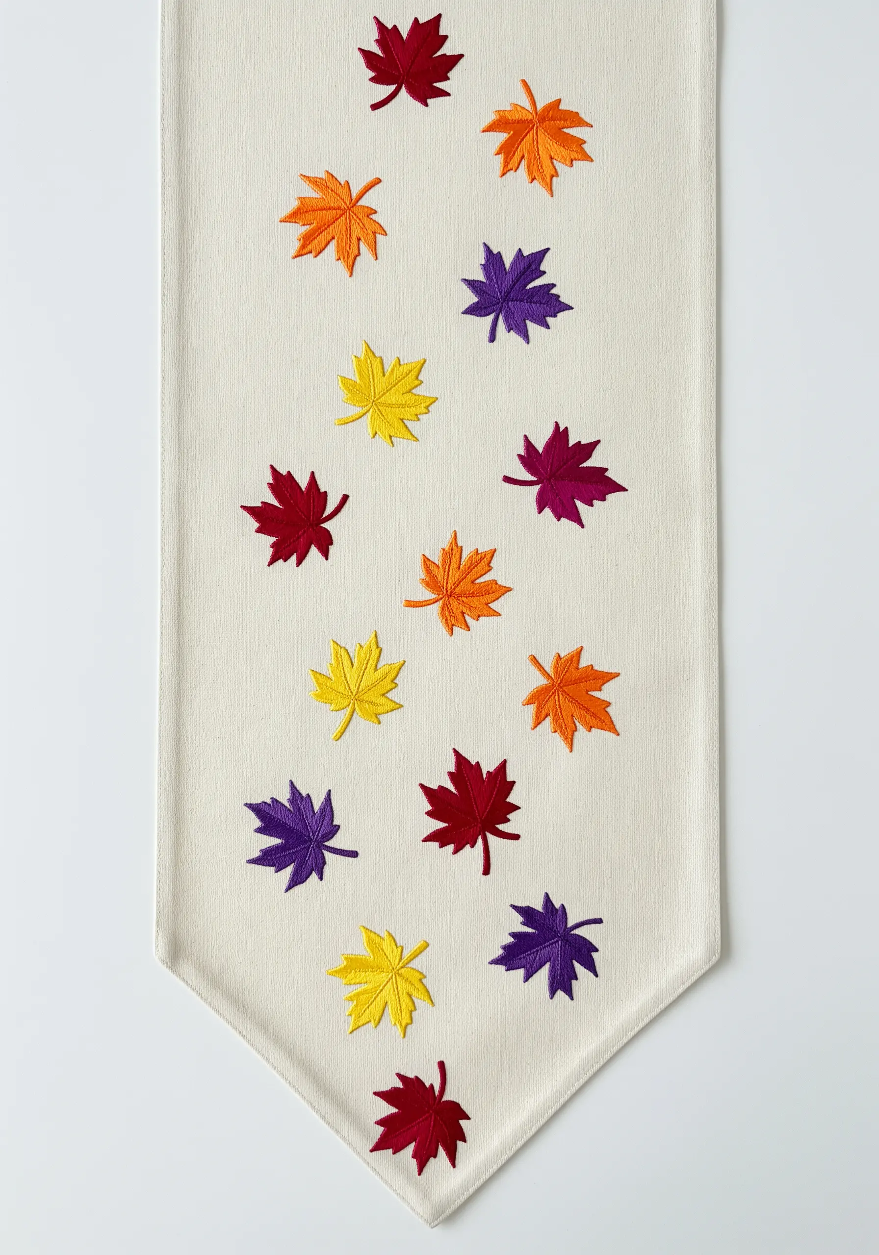 Scattered maple leaves in a rainbow of autumnal colors on a linen table runner.