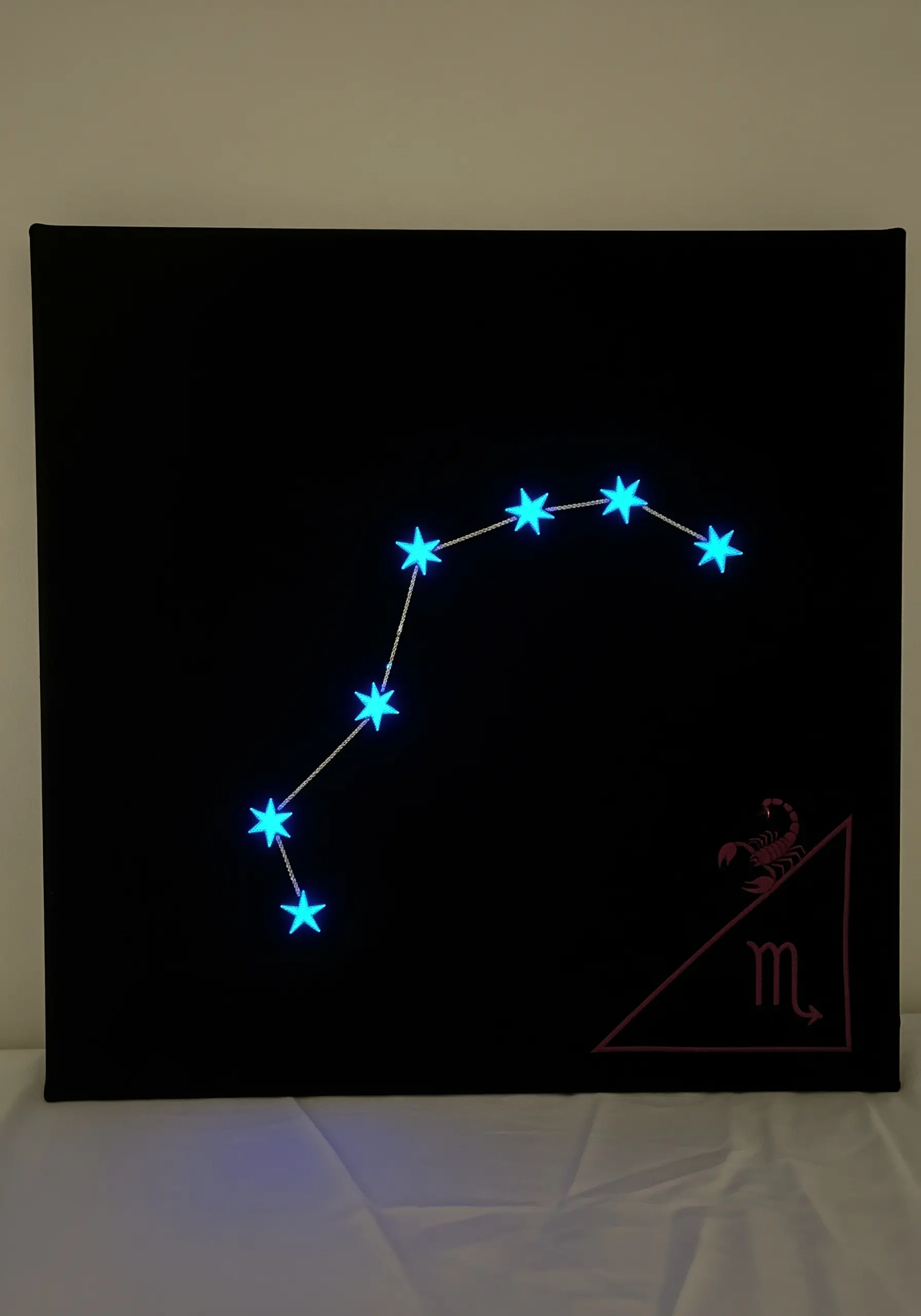 Scorpio constellation embroidered with glow-in-the-dark thread on a black canvas.