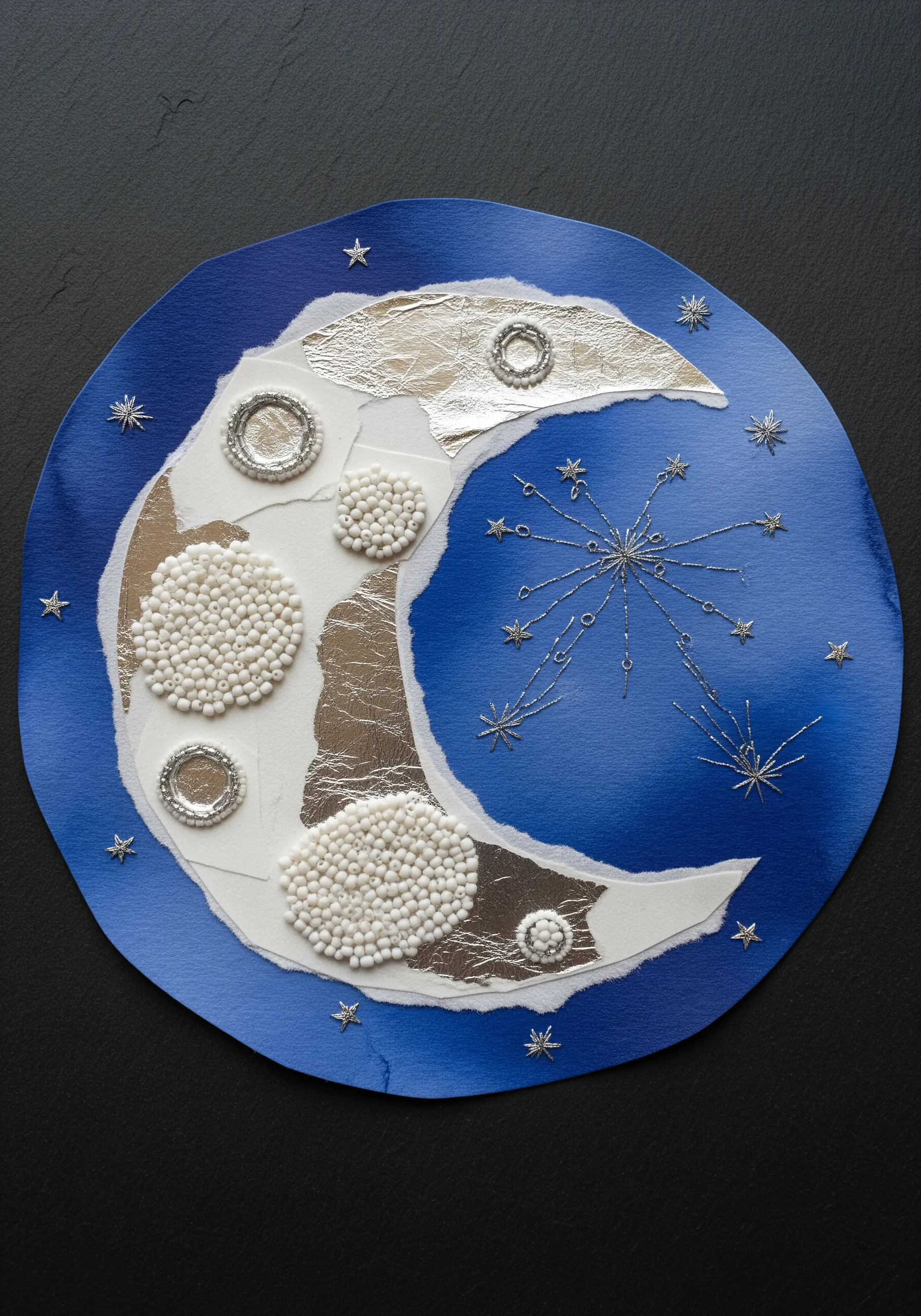 A mixed-media moon collage with white bead textures, silver foil, and embroidered stars.