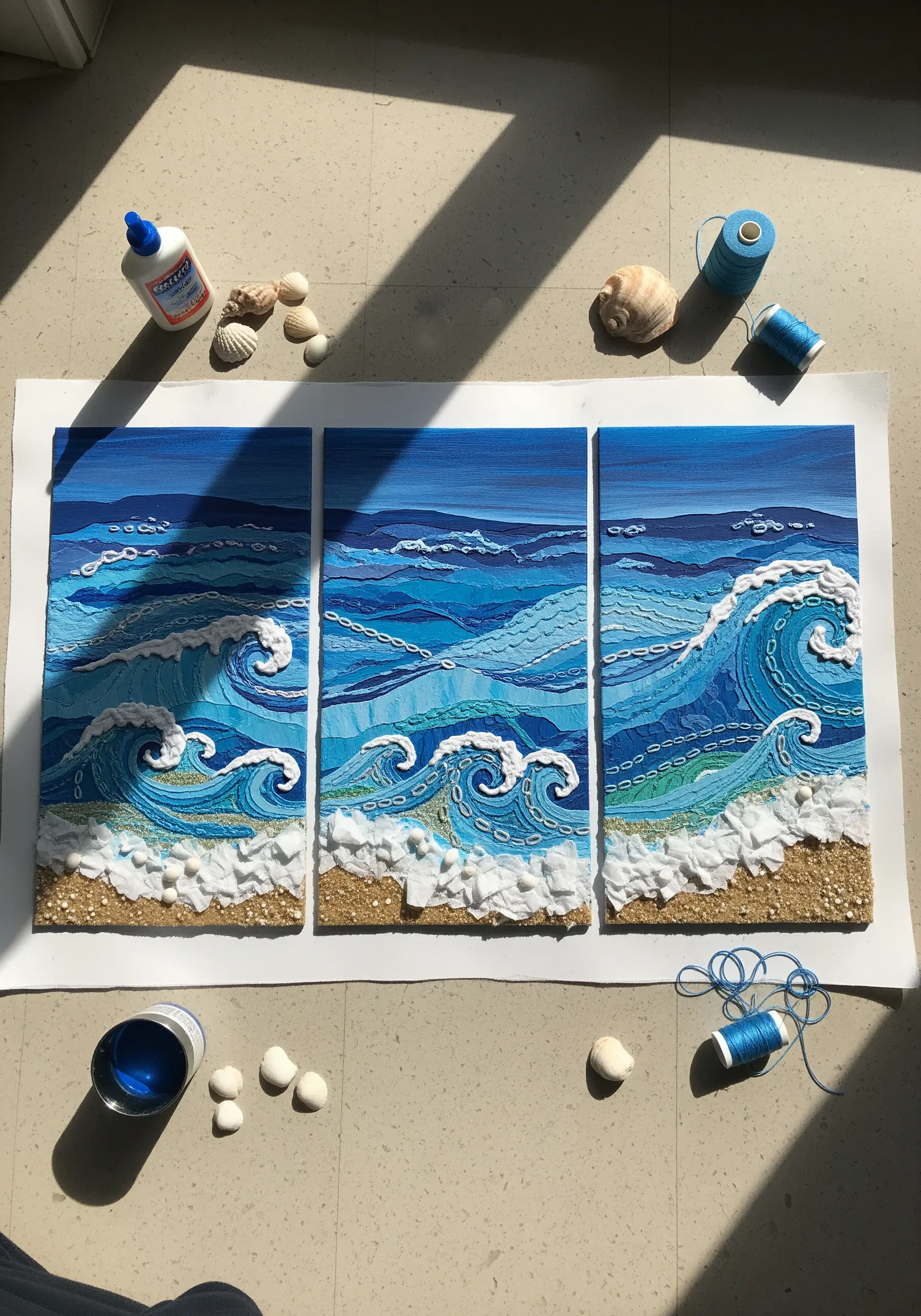 A triptych of ocean waves made from layered fabric, yarn, and stitched details.
