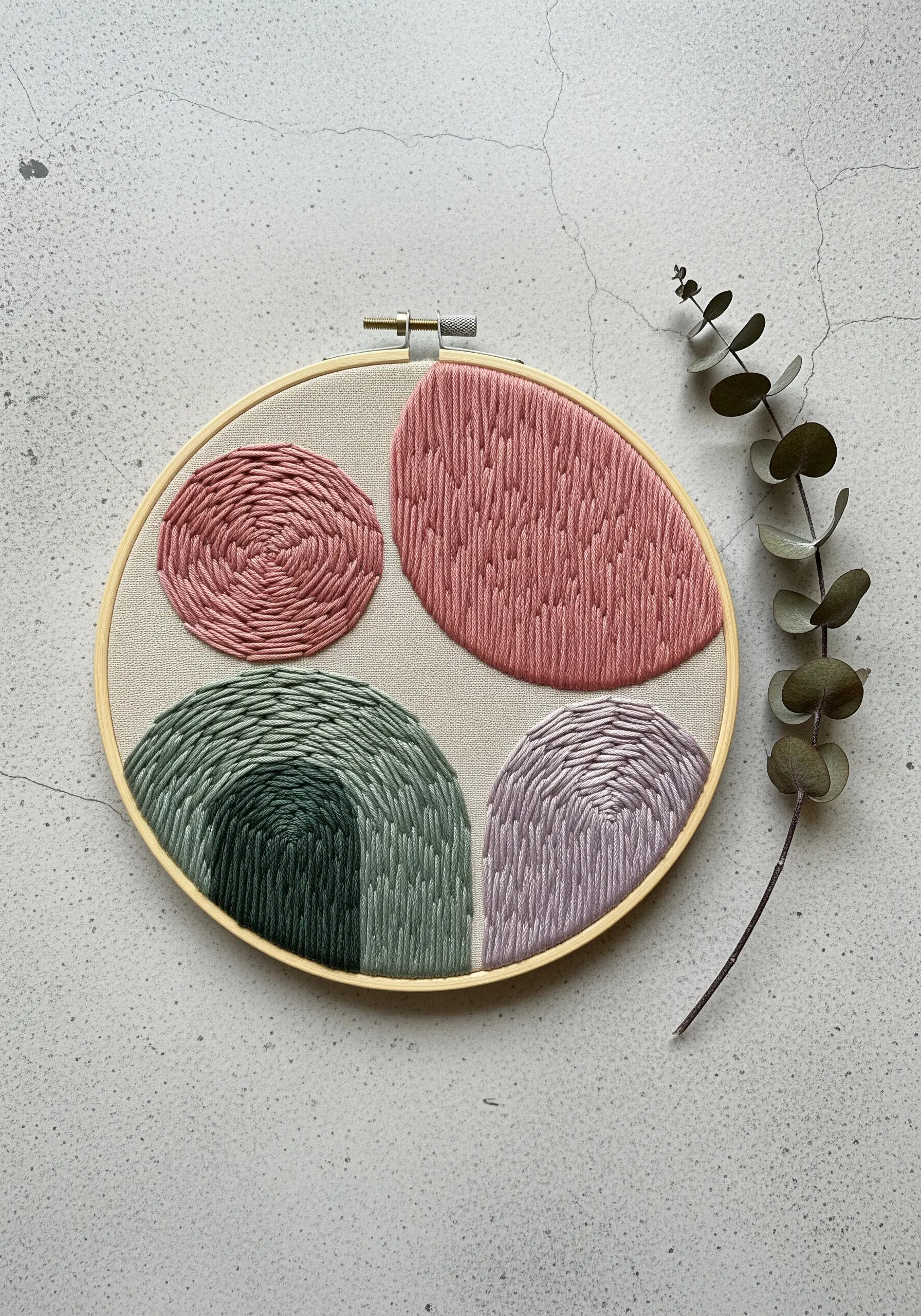 Abstract hoop art with pink, green, and lavender directional fill stitches.
