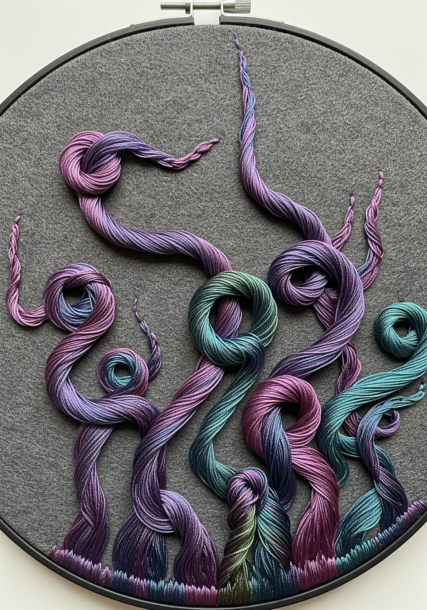 Sculptural, twisted cords made from variegated thread, couched onto grey fabric.