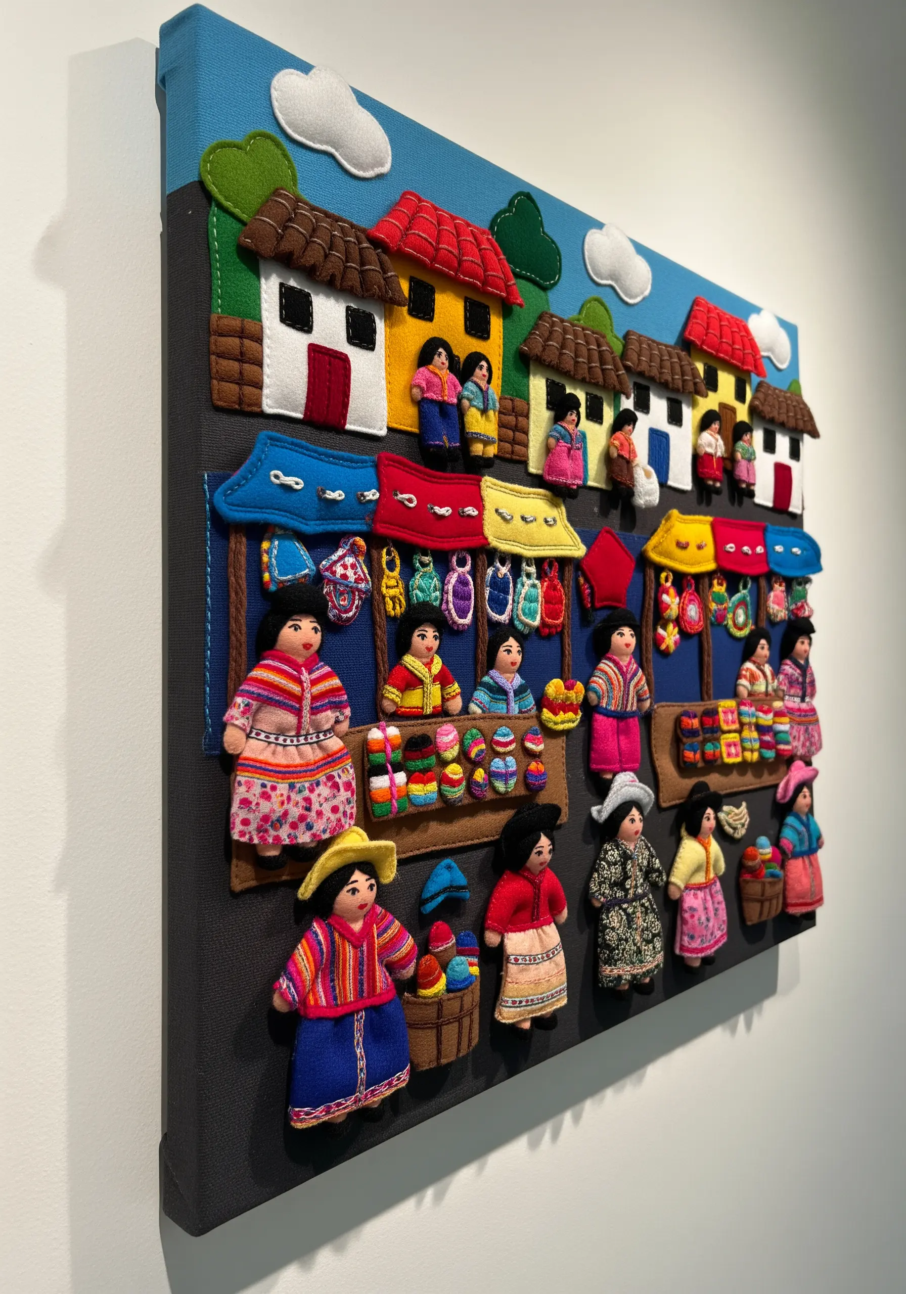 Three-dimensional wall art of a Peruvian market scene made from layered felt and fabric.