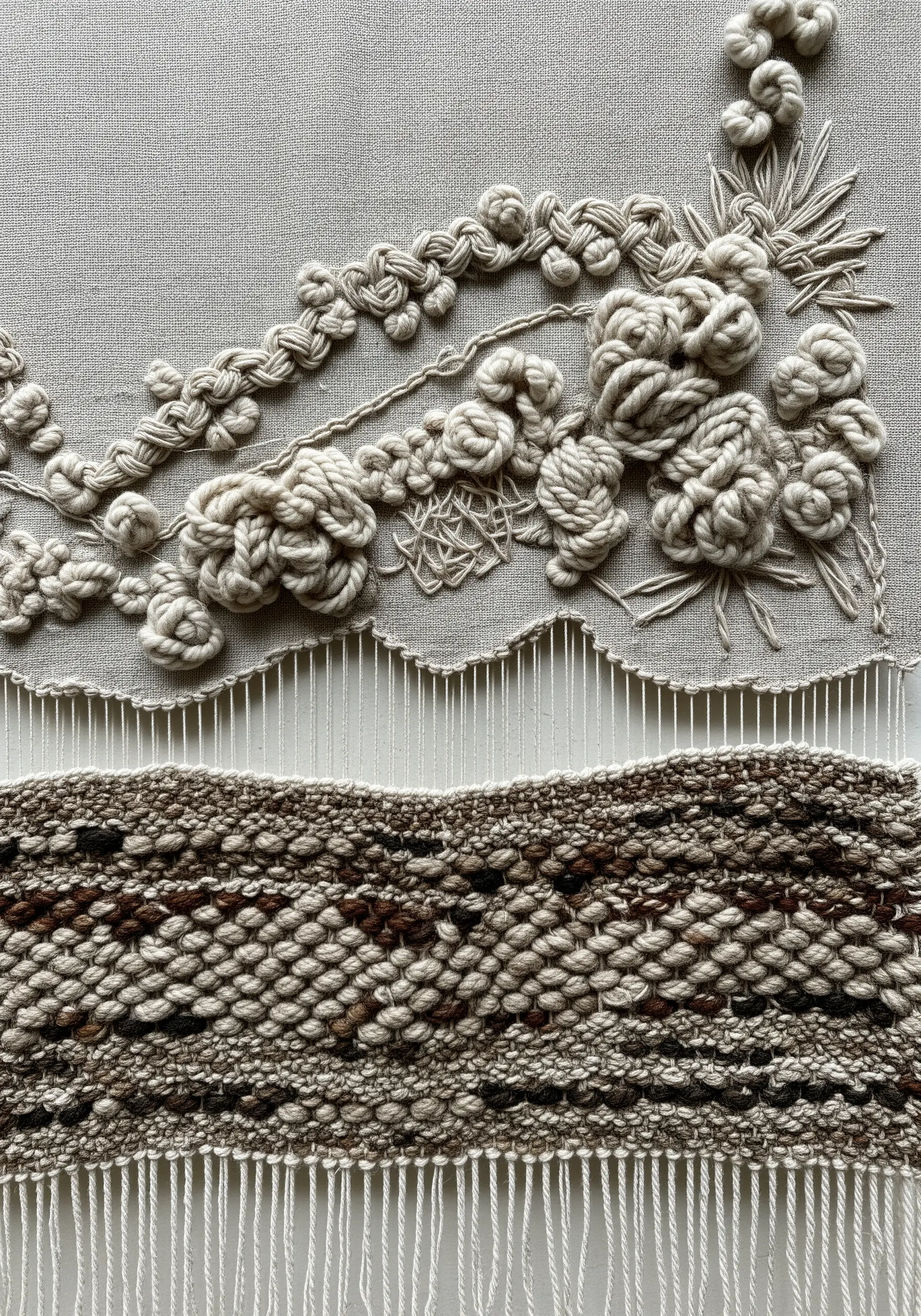 Monochrome fiber art combining weaving, macrame knots, and embroidery on canvas.