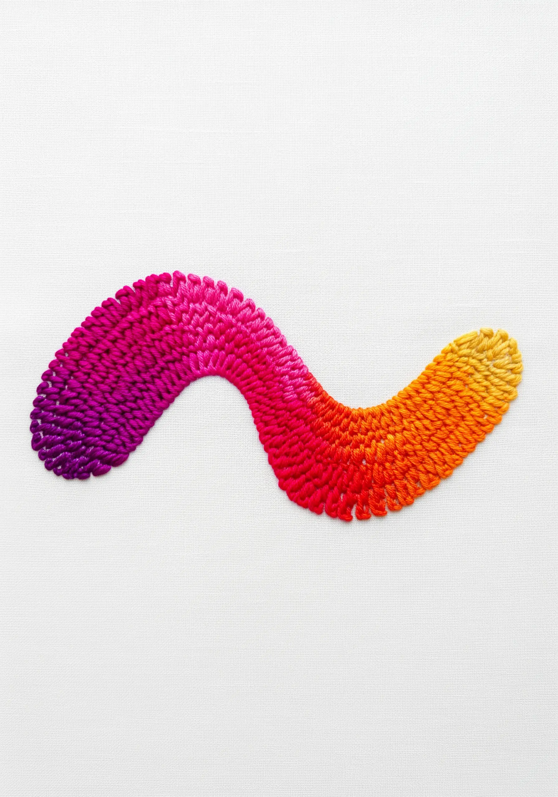 A smooth, thread-painted gradient from magenta to yellow in a flowing, abstract shape.