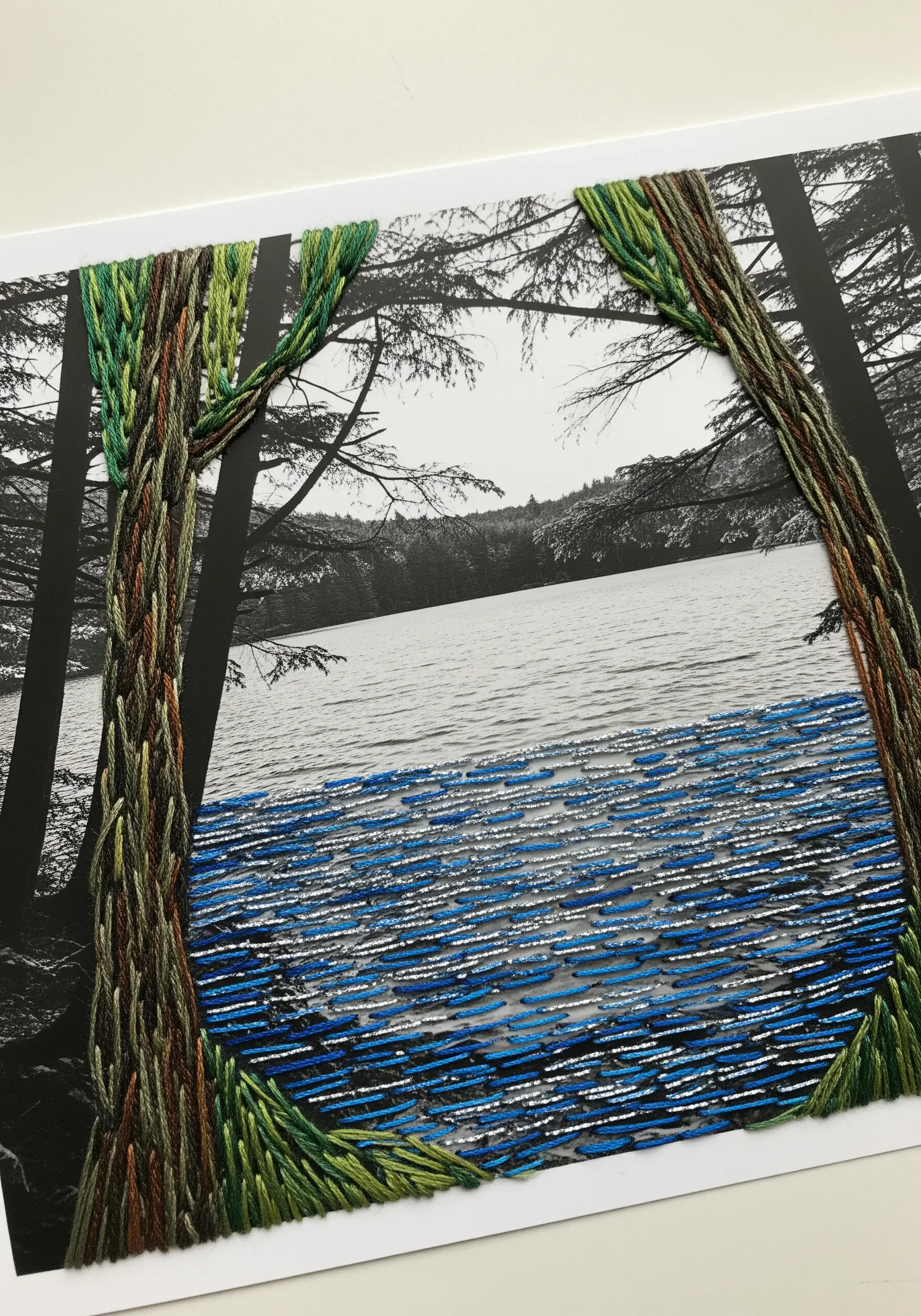 A black-and-white photograph of a lake scene with embroidered trees and water in full color.