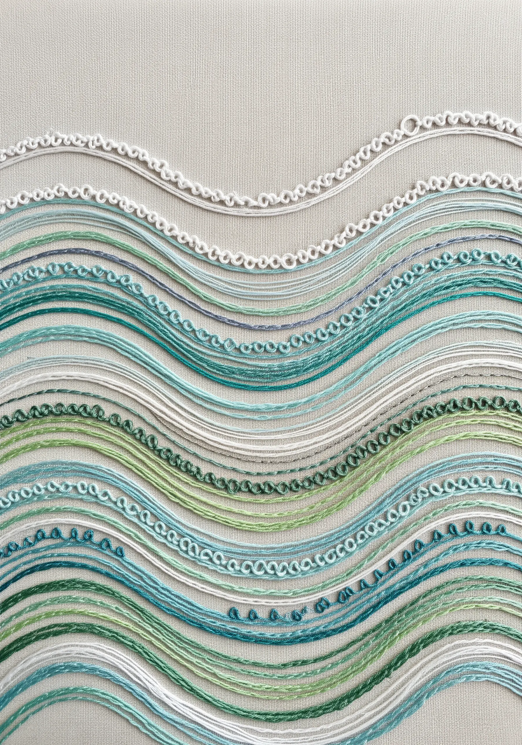 Parallel wavy lines stitched in various shades of green and blue, each with a different stitch texture.