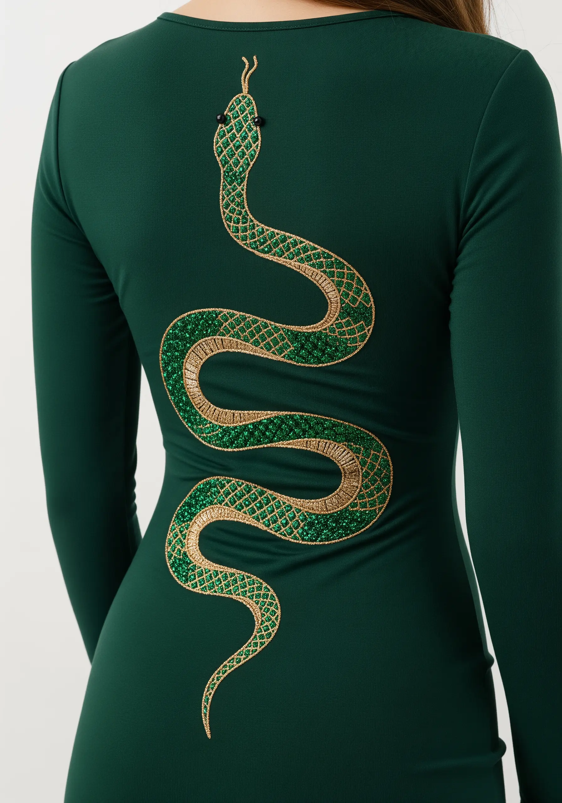 A large snake embroidered with green and gold glitter thread on the back of a green dress.