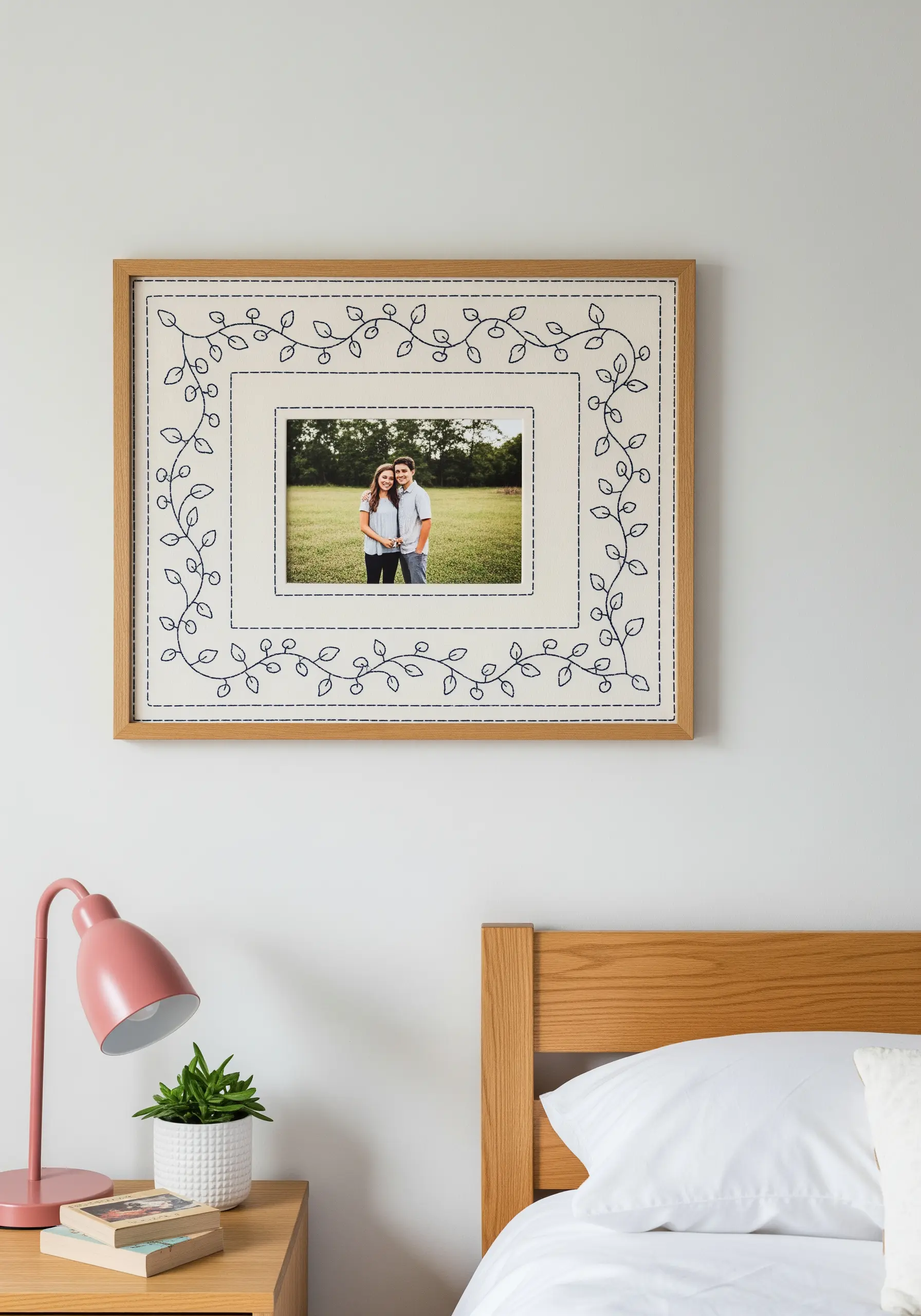 A photo frame with an embroidered mat featuring a delicate running-stitch vine border.