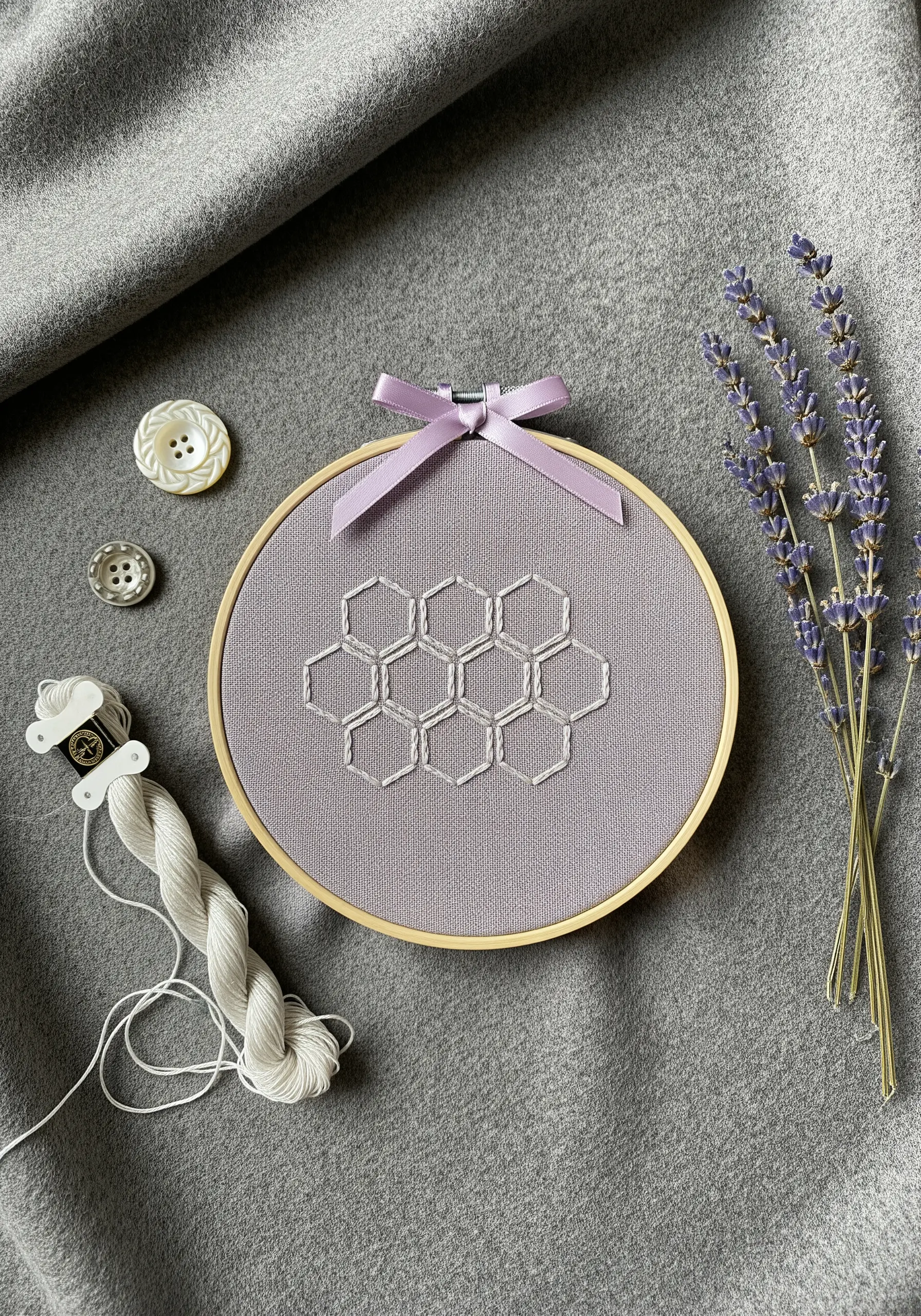 A delicate white backstitched honeycomb pattern on a lilac-colored fabric.